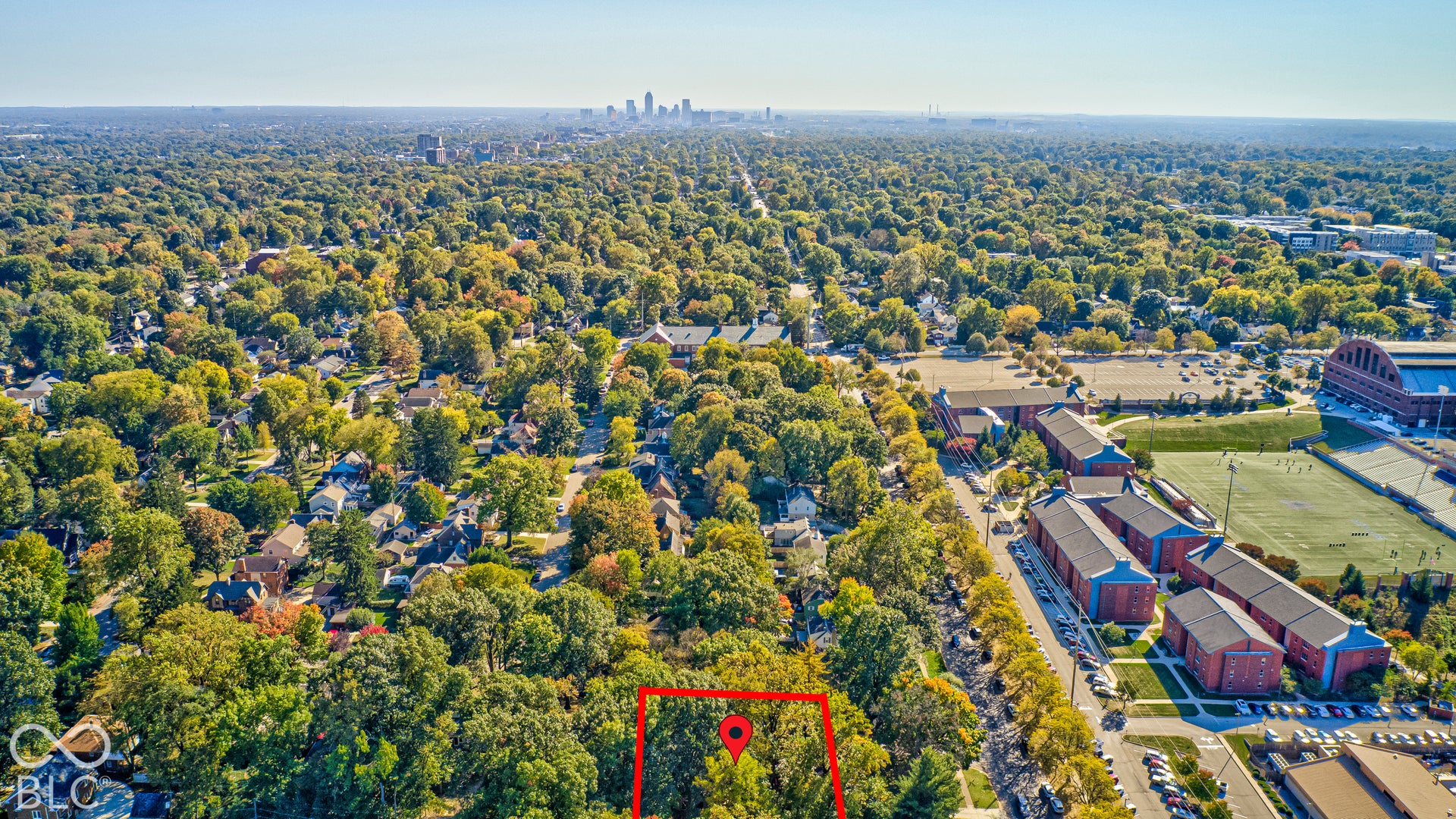 Butler University and the downtown Indianapolis skyline beyond, with the home marked among the trees. City access with the privacy of a wooded ravine lot.