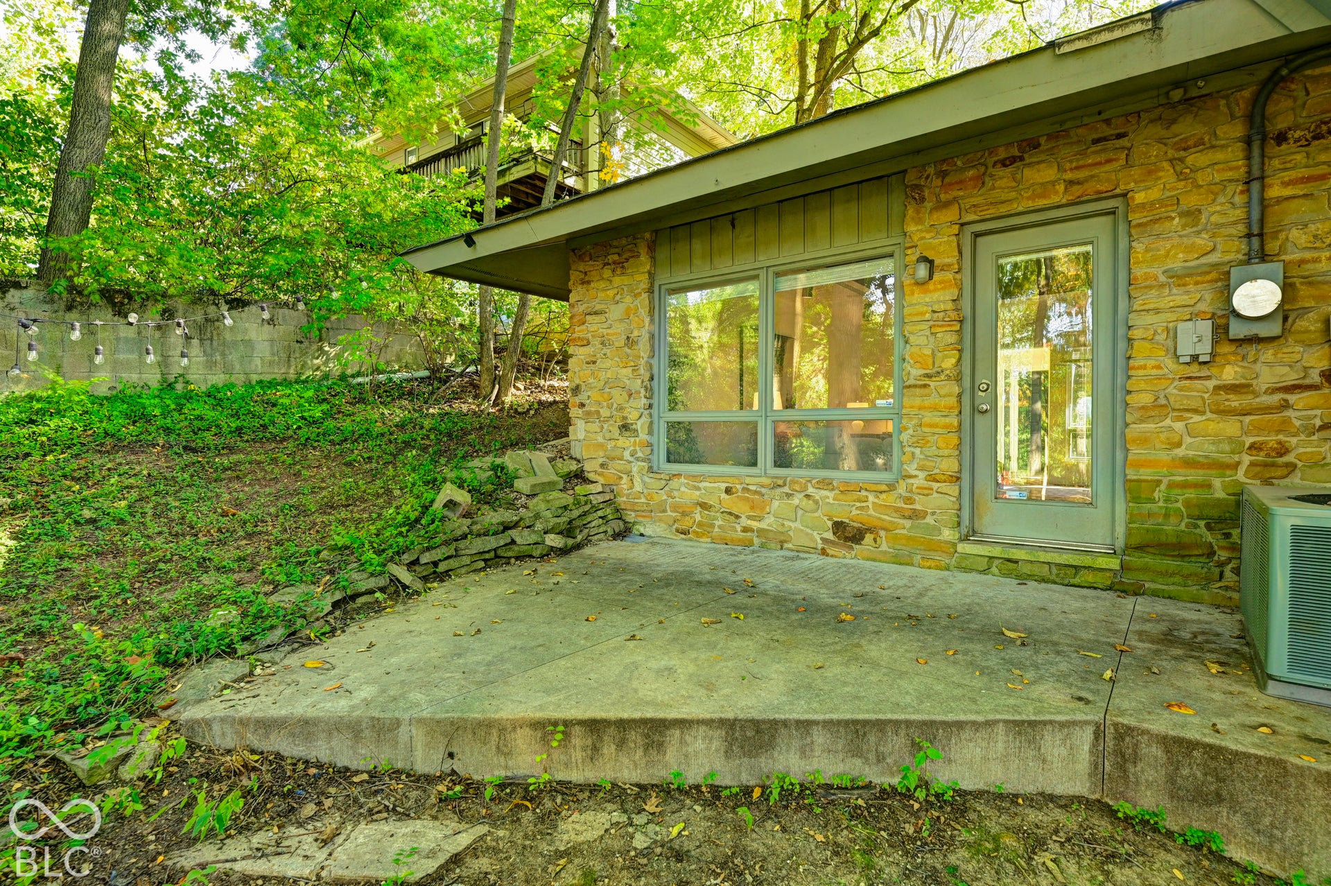 Stone and glass at the family room patio, sheltered by a deep roof overhang. A side door brings friends straight in from the yard.
