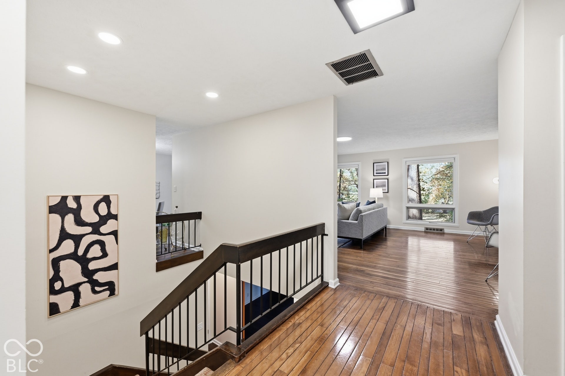 From the foyer the plan flows open in every direction, decades ahead of its time: hardwood floors, clean lines and windows into the trees at the far end of the living room.