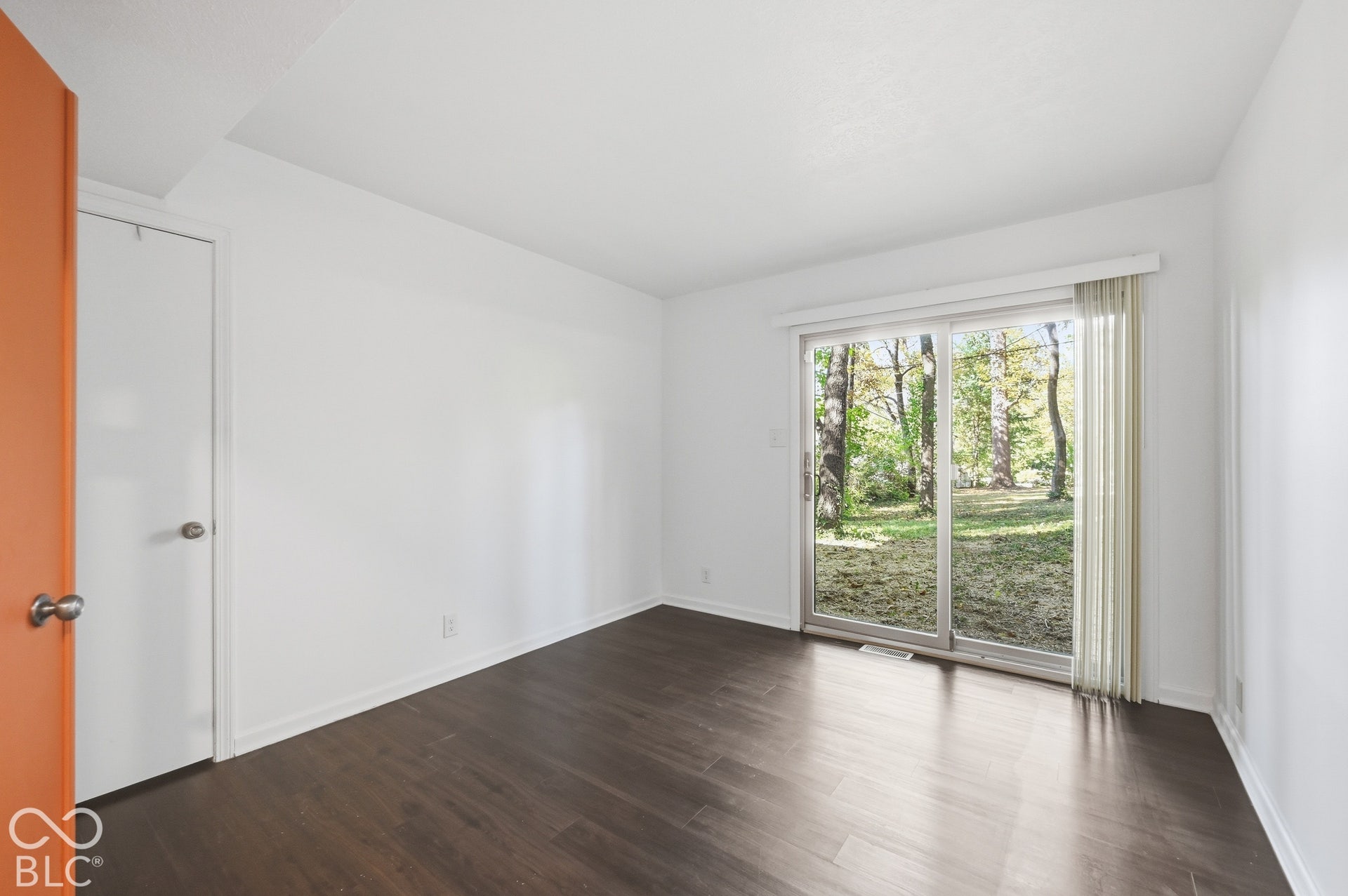 Lower-level bedroom with a sliding door straight out to the wooded backyard. The architect's daughter remembers spring Saturdays napping here with the door open to the trees.