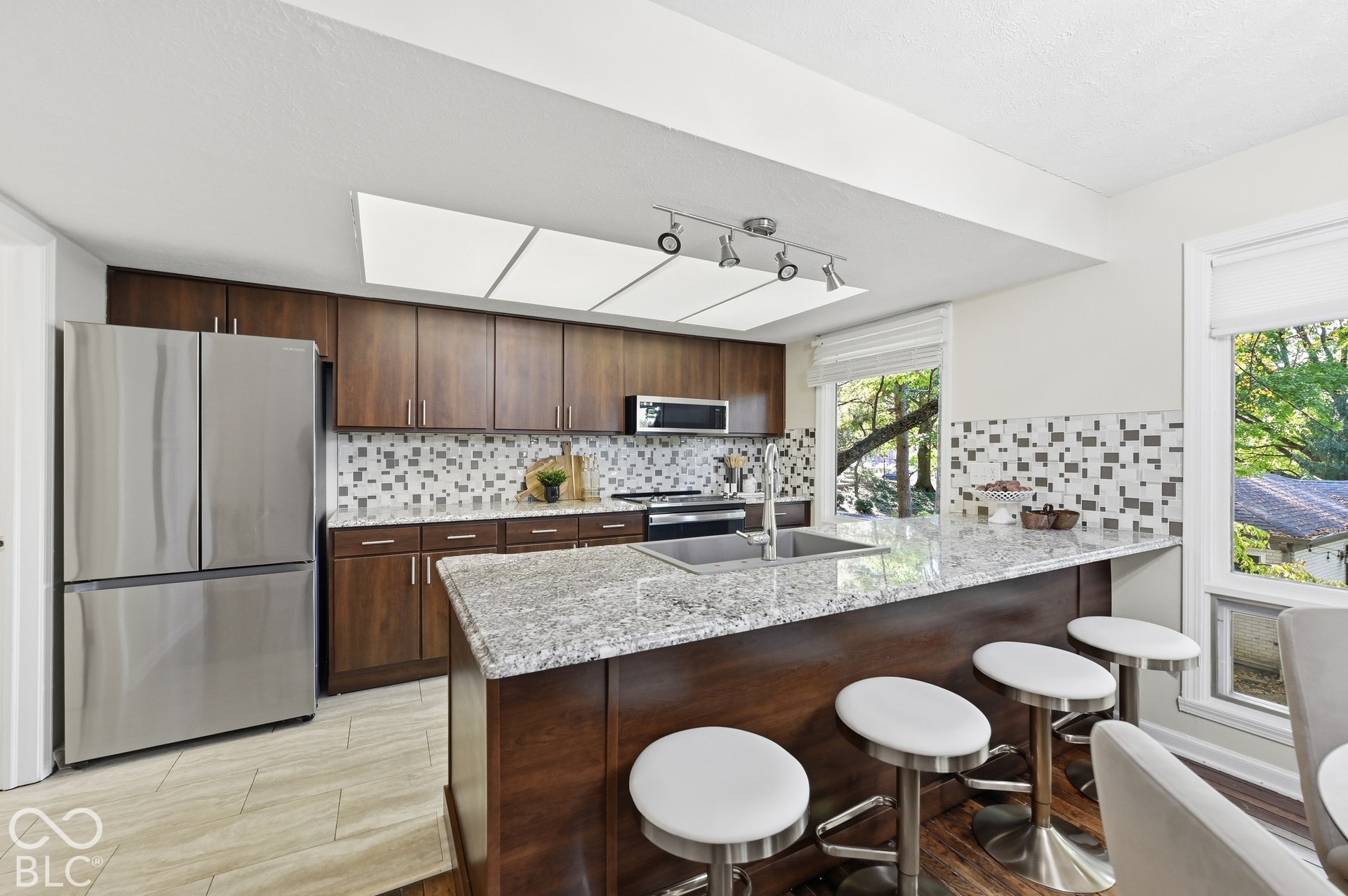 Updated kitchen with granite counters, breakfast bar, stainless appliances and mosaic tile backsplash, open to the dining room across the bar exactly as the architect designed it.