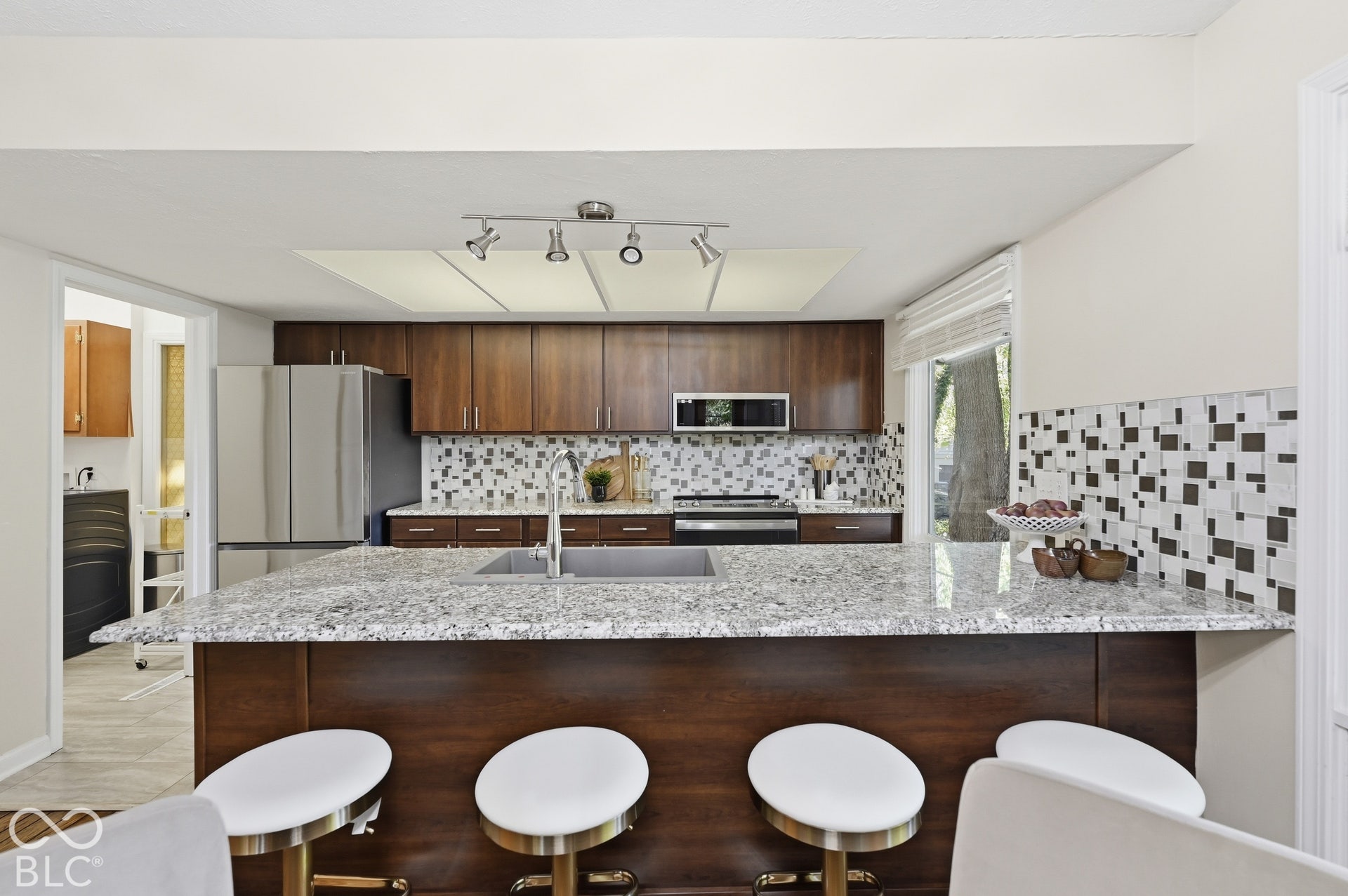 Breakfast bar seating for four, granite surfaces and updated cabinetry. The kitchen connects to the dining room across the bar, keeping the cook in the conversation.