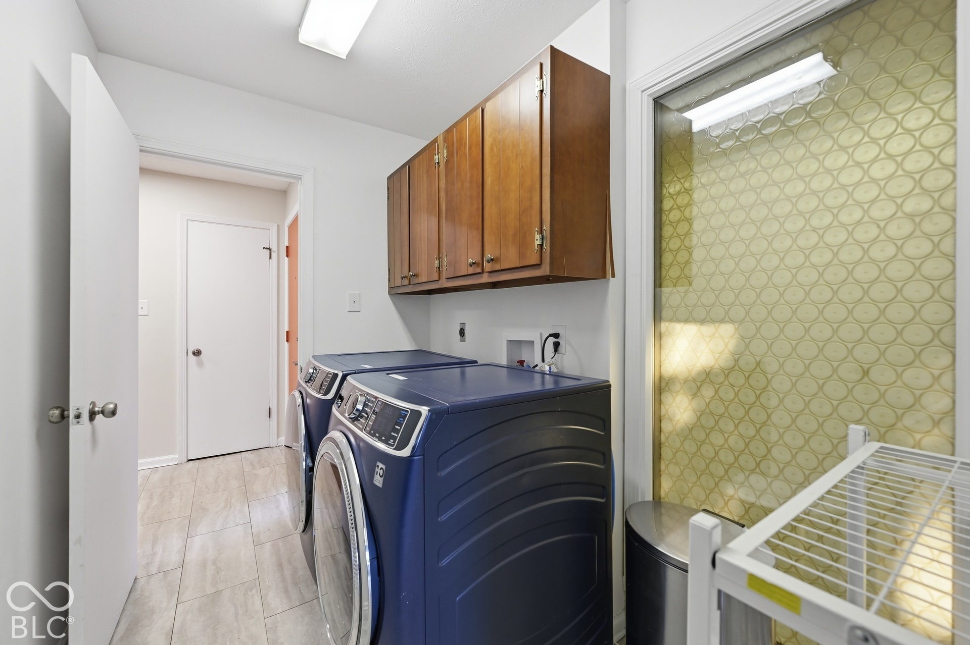 Laundry room that doubles as a mudroom off the front entry, with a shortcut to the kitchen, built-in cabinetry and the original patterned glass panel.