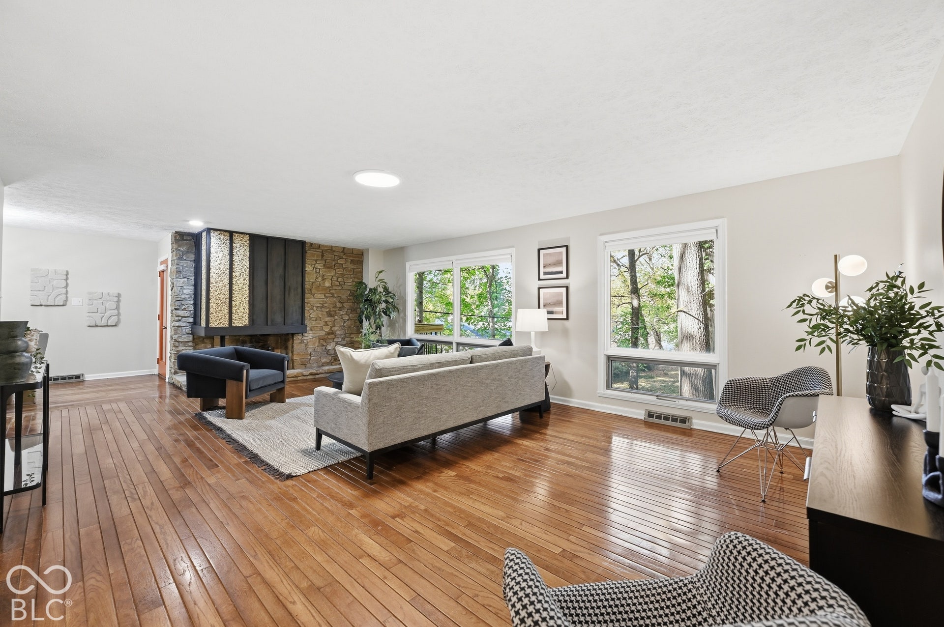 The long living room runs the full back of the house, with north-facing windows placed by design for soft, even natural light all day and a stone fireplace anchoring the room.