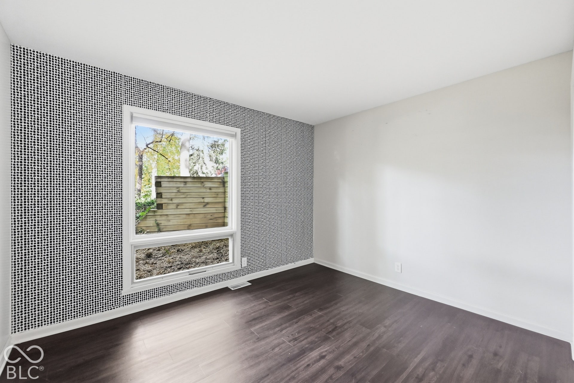 Third bedroom with a statement accent wall and a window framing the hillside. Built into the hill, this room has sheltered three generations of the Woods family.