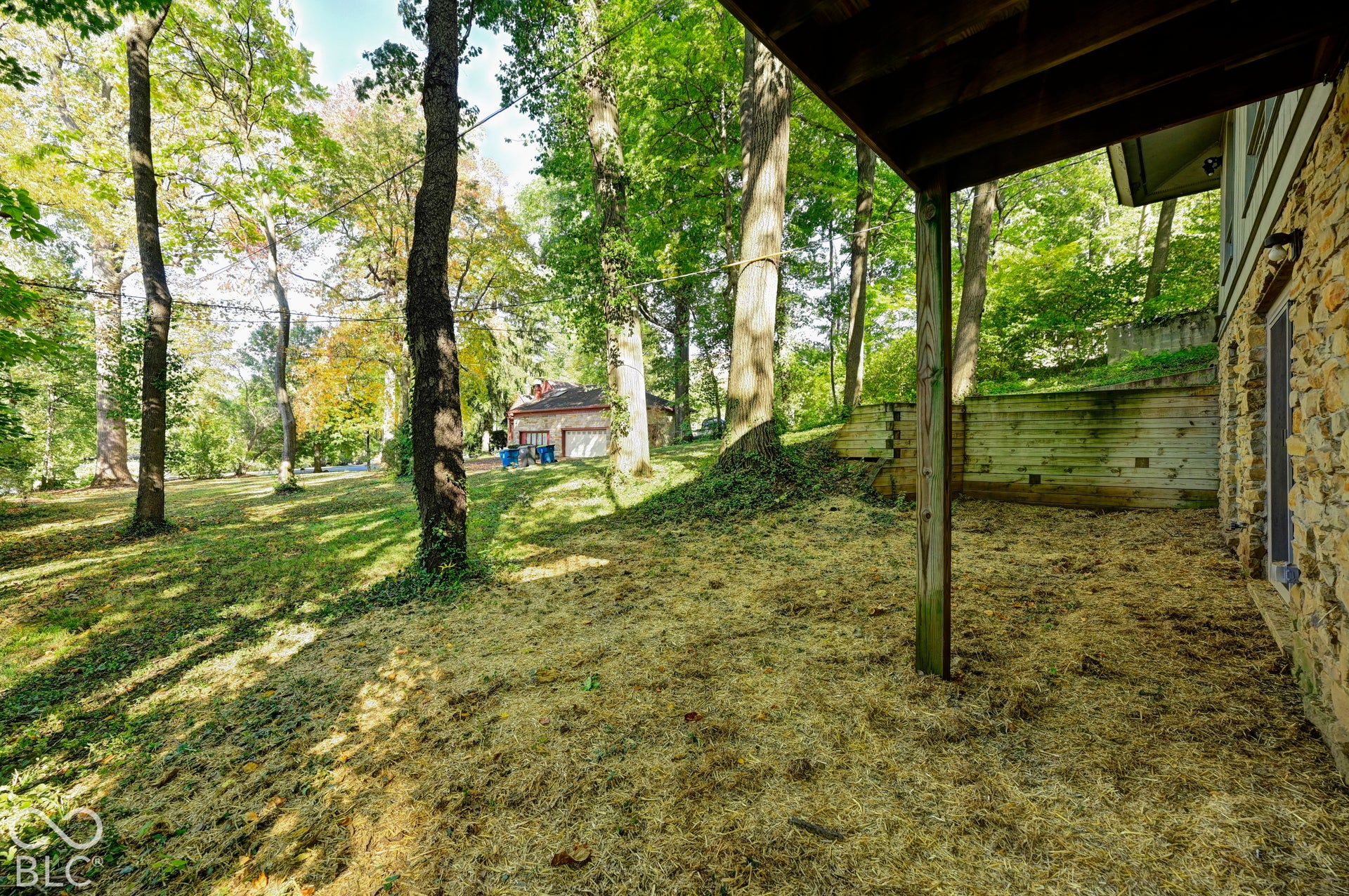 Deep eaves overhang the sheltered lower-level walk-out, with the wooded ravine stretching beyond.