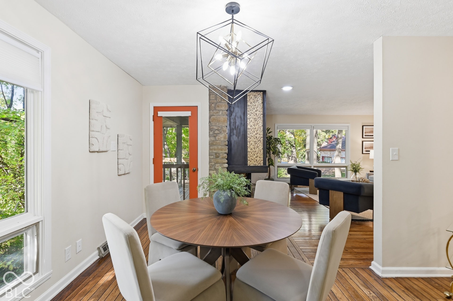 Dining room bathed in light from the window wall, with the two-sided fireplace and living room just beyond. Easy flow for entertaining.