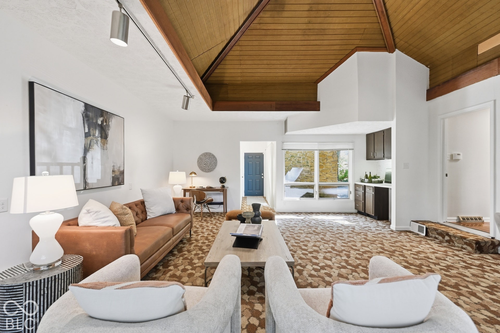 Under the wood pyramid ceiling, the 1974 family room offers flexible space for lounging, dining, a studio or play, with a hallway leading straight to the attached garage.