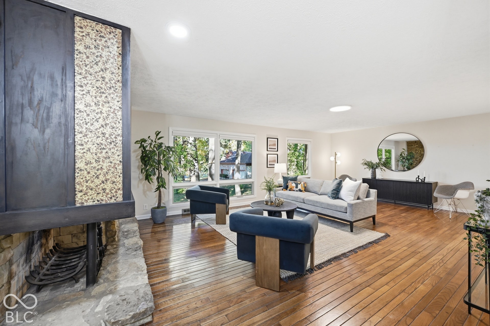 Two-sided fireplace detail: stacked stone, raised stone hearth and the original dark wood surround with textured mosaic inlay. A one-of-one architectural moment in Butler-Tarkington.