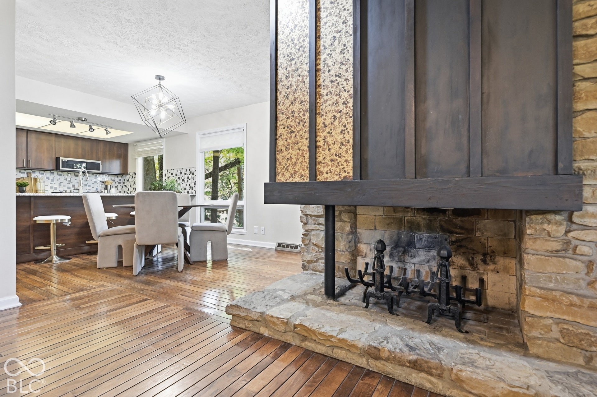 The see-through stone fireplace opens to both the living and dining rooms, with the updated kitchen beyond. Original stone hearth, custom ironwork and hardwood floors.