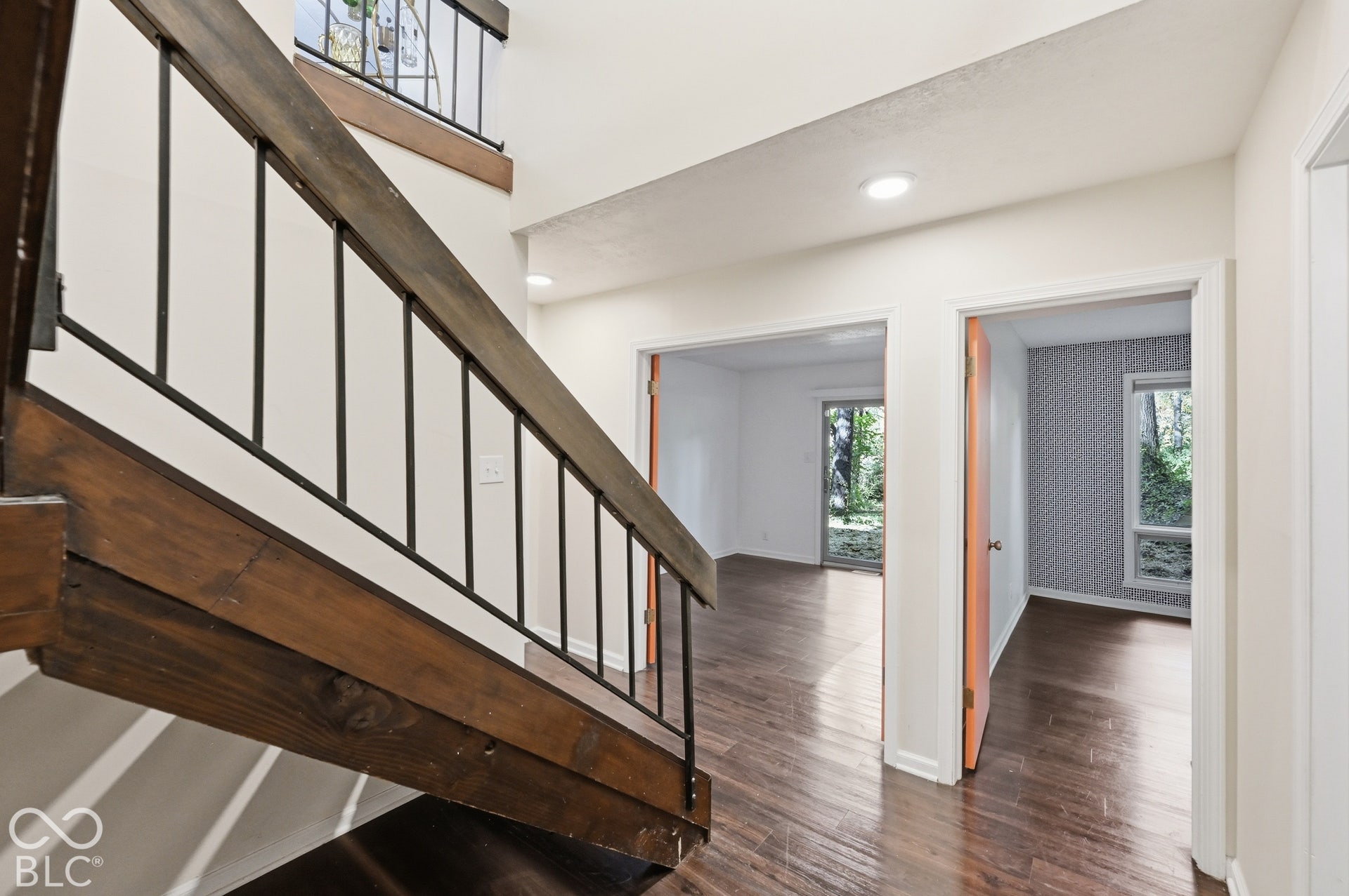 A double-height stairwell with an open, floating staircase, one of the home's most dramatic architectural moments. The bedrooms open off the lower hall.