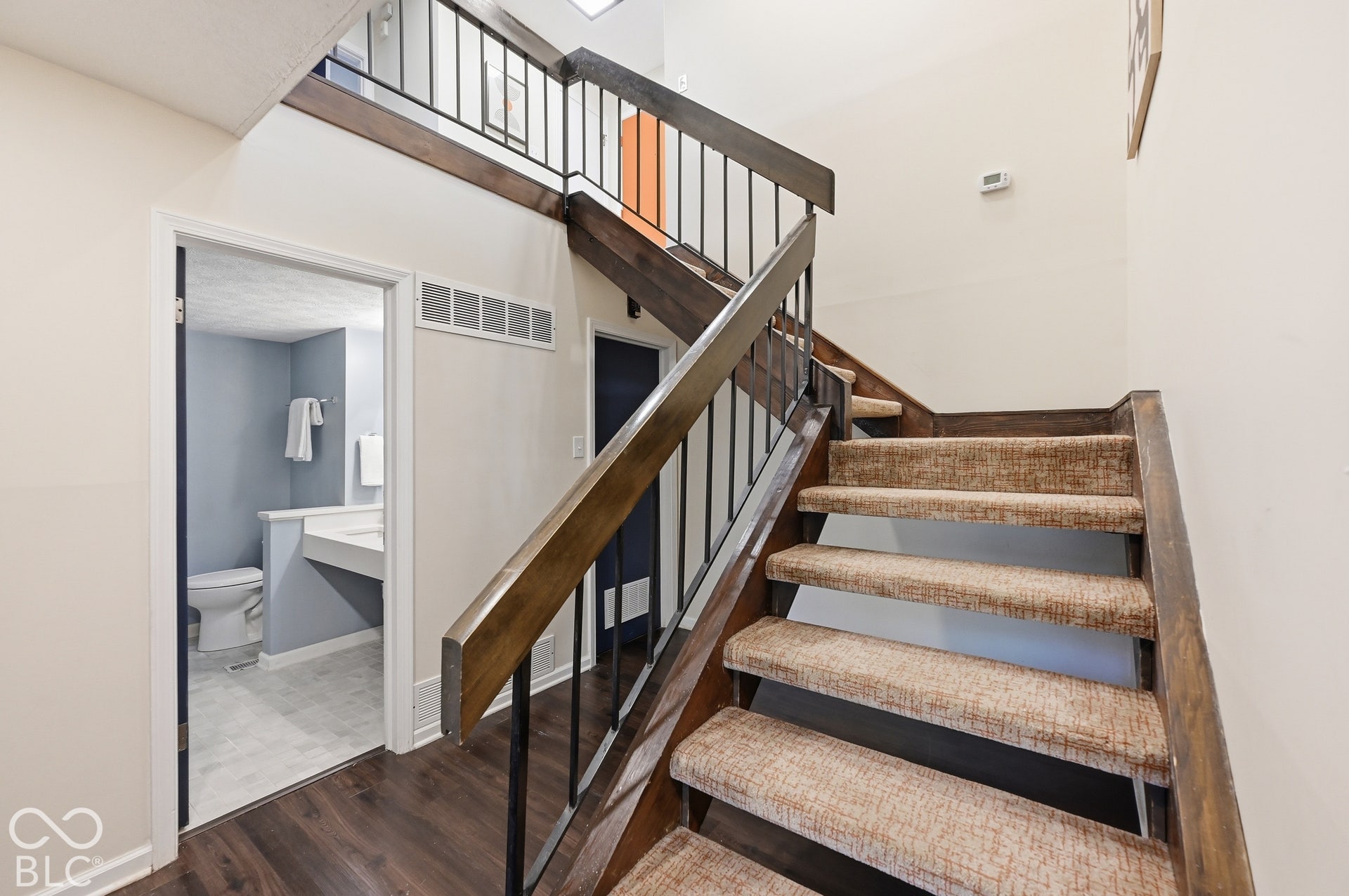 The floating staircase with slim iron balusters leads down to the lower-level bedrooms and a full bath.