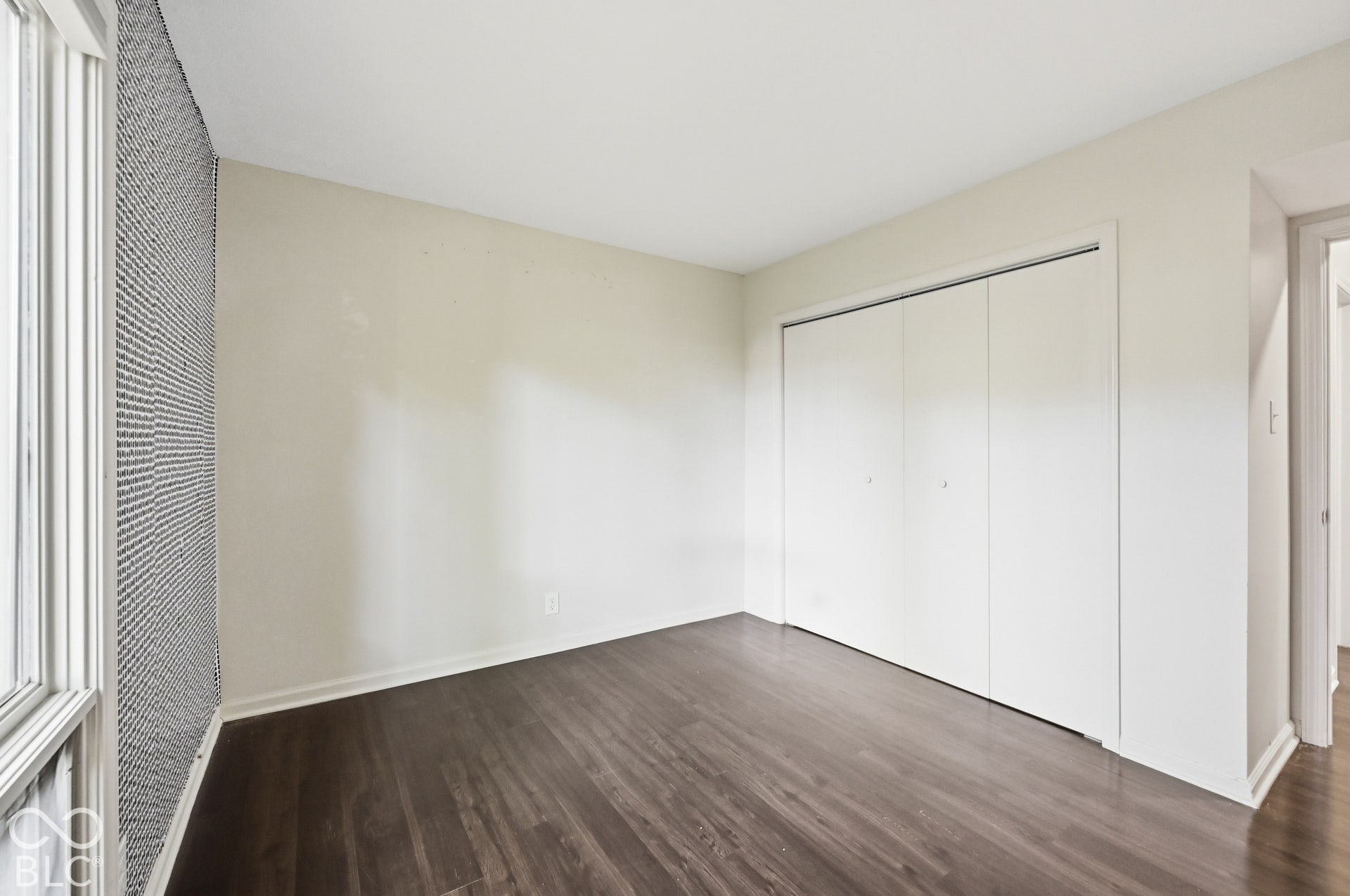 Third bedroom with a full-wall closet and dark-tone floors, ready for guests, a nursery or a home office.