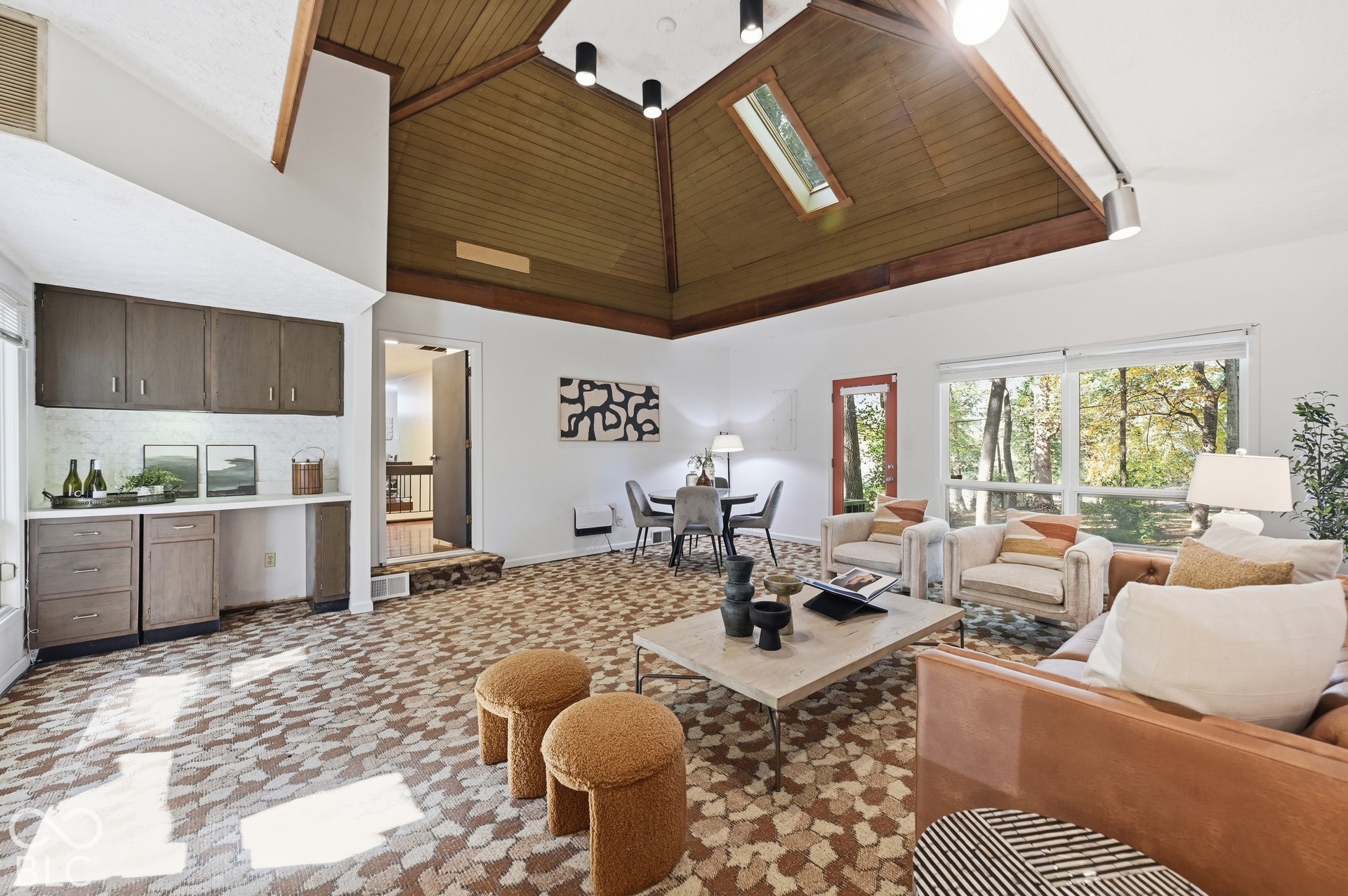 The family room's dry bar and built-in cabinetry sit beneath the soaring wood pyramid ceiling, with a dining area by the windows. Ready for game nights, entertaining or a home office.