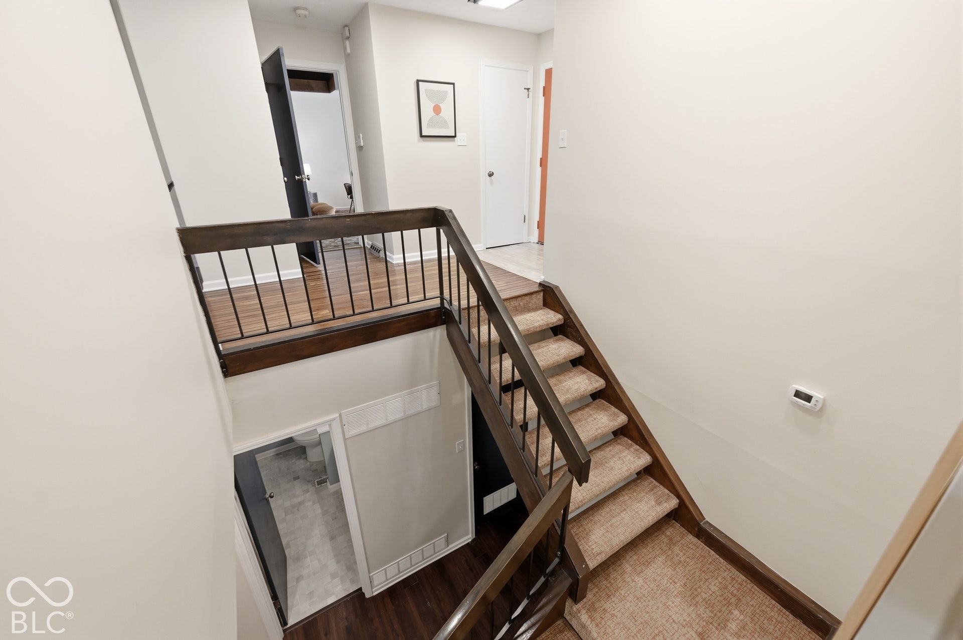 The open staircase descends from the main level to the walk-out lower level, where all three bedrooms sit tucked into the hillside among the trees.