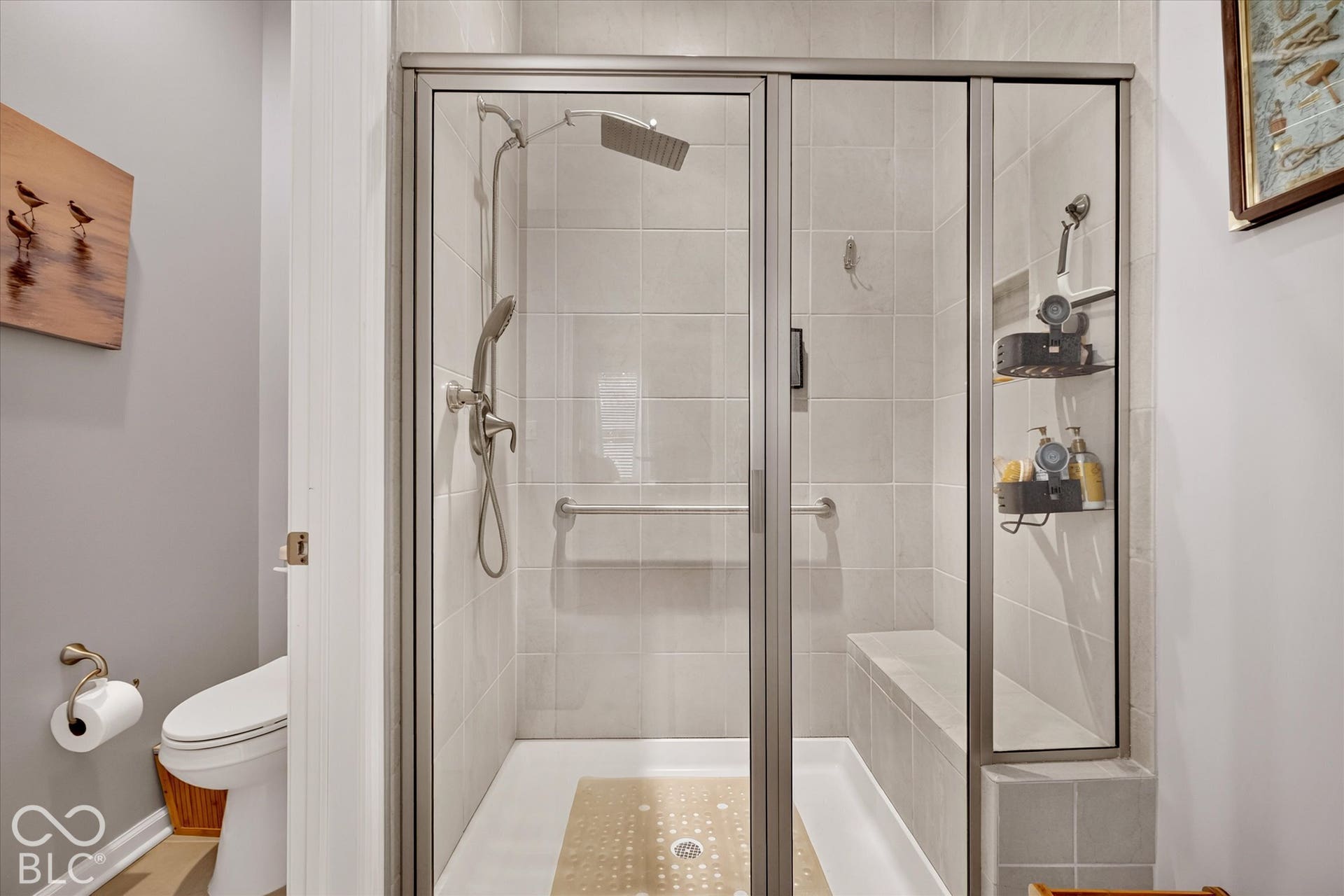 Enclosed shower with a glass door, tile surround, integrated bench, and a rain showerhead