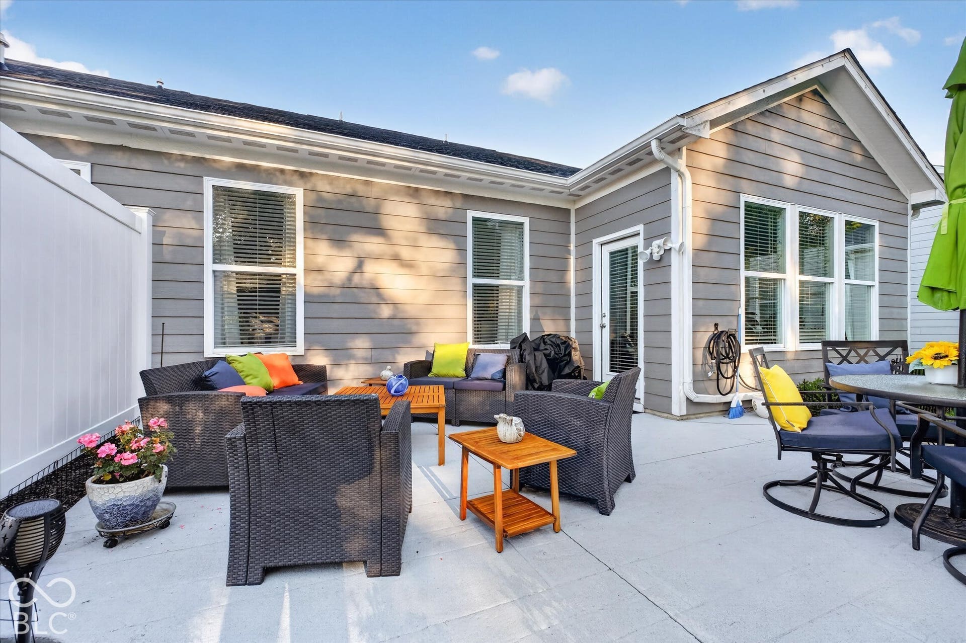 Expansive concrete patio with a white privacy fence