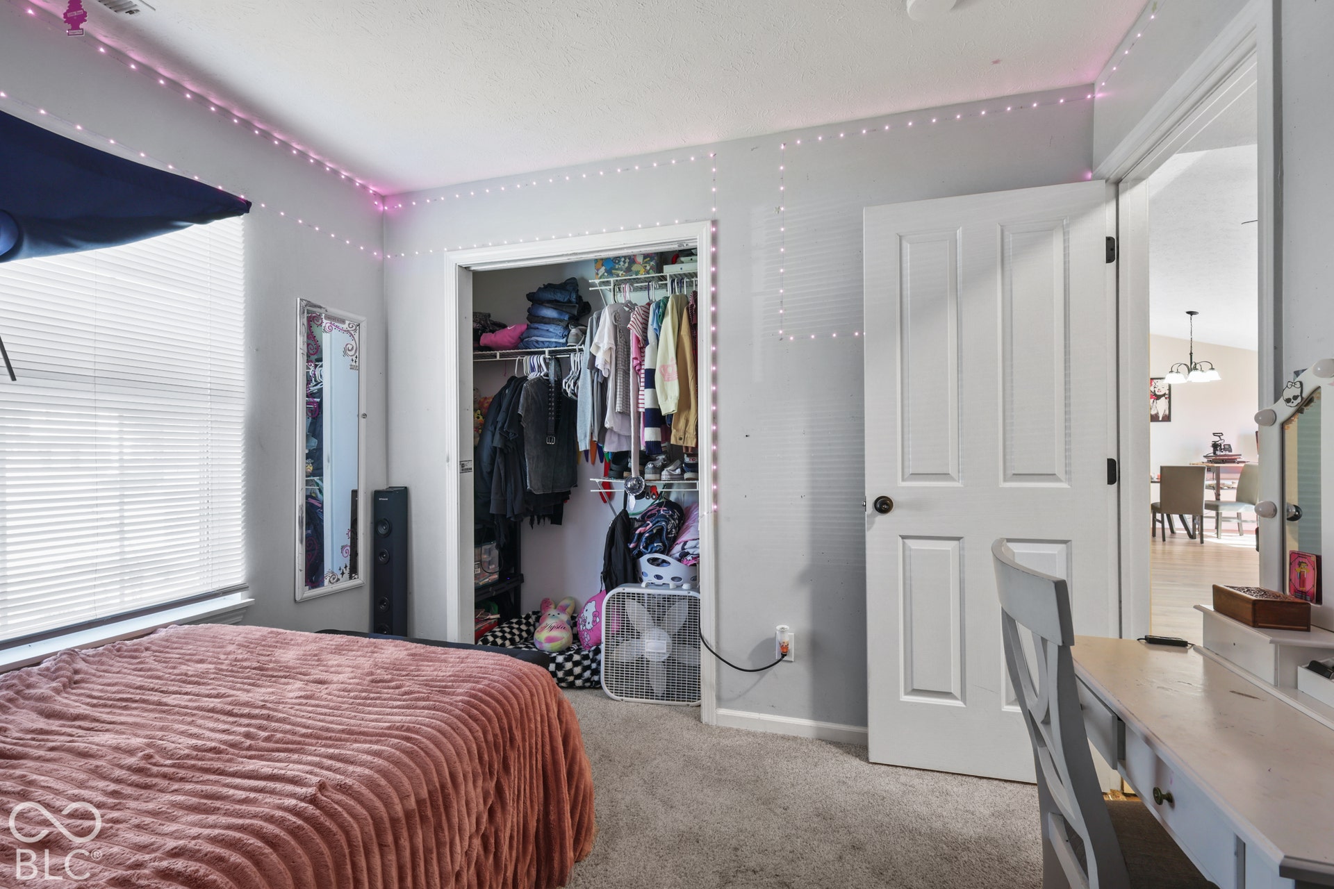 Carpeted flooring, window with blinds, bi-fold closet doors, and white paneled interior door