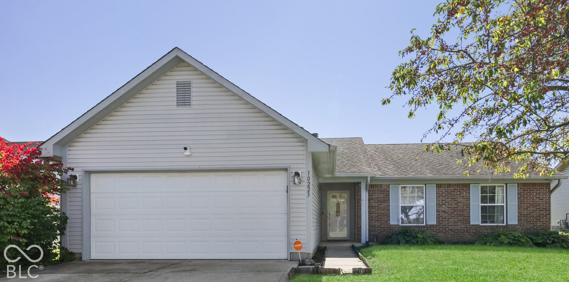 Single-story residence featuring a two-car garage, brick facade accents, and a front entry with sidelights