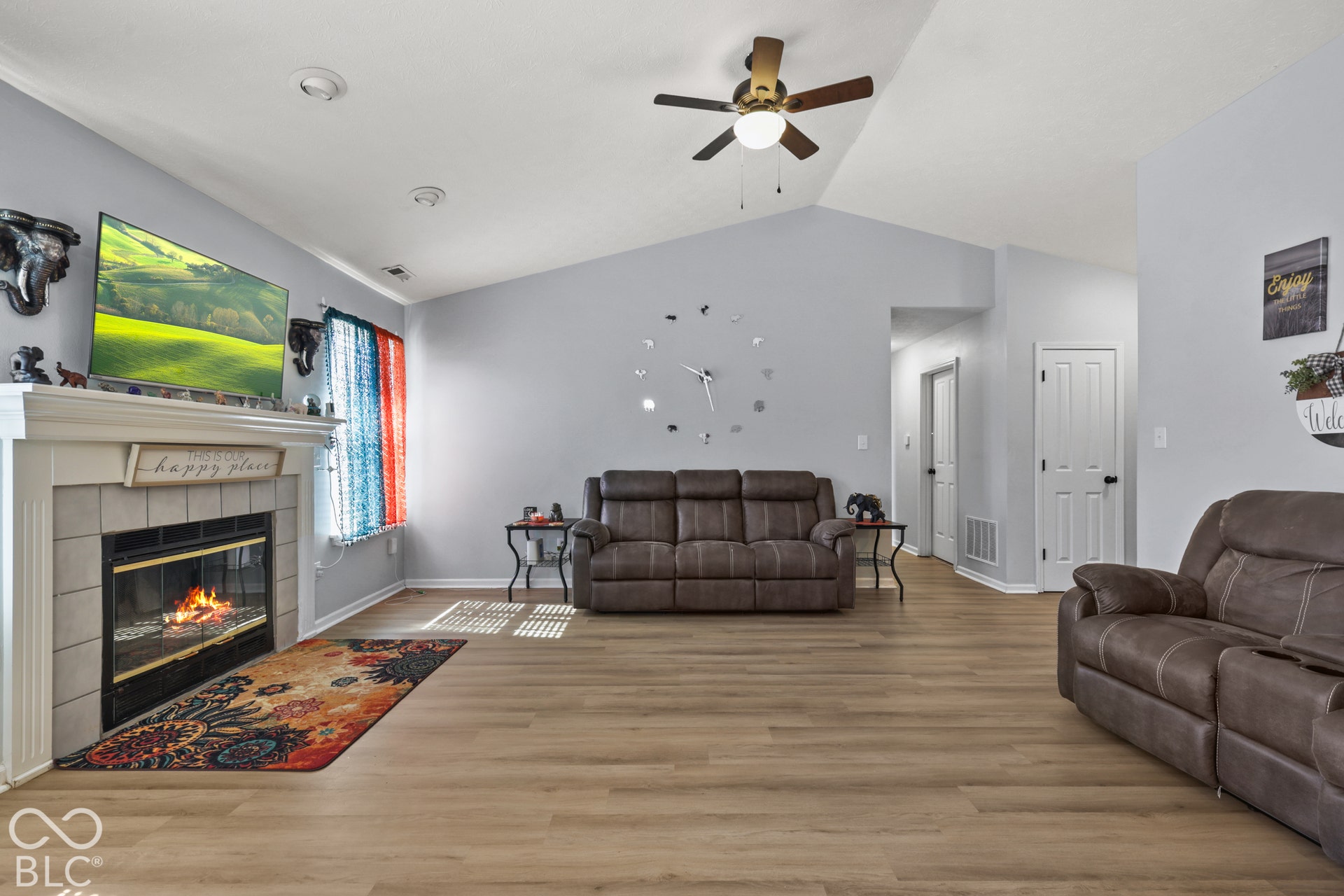 Vaulted ceiling, wood-finish flooring, fireplace with tile surround, ceiling fan with integrated lighting, recessed lighting