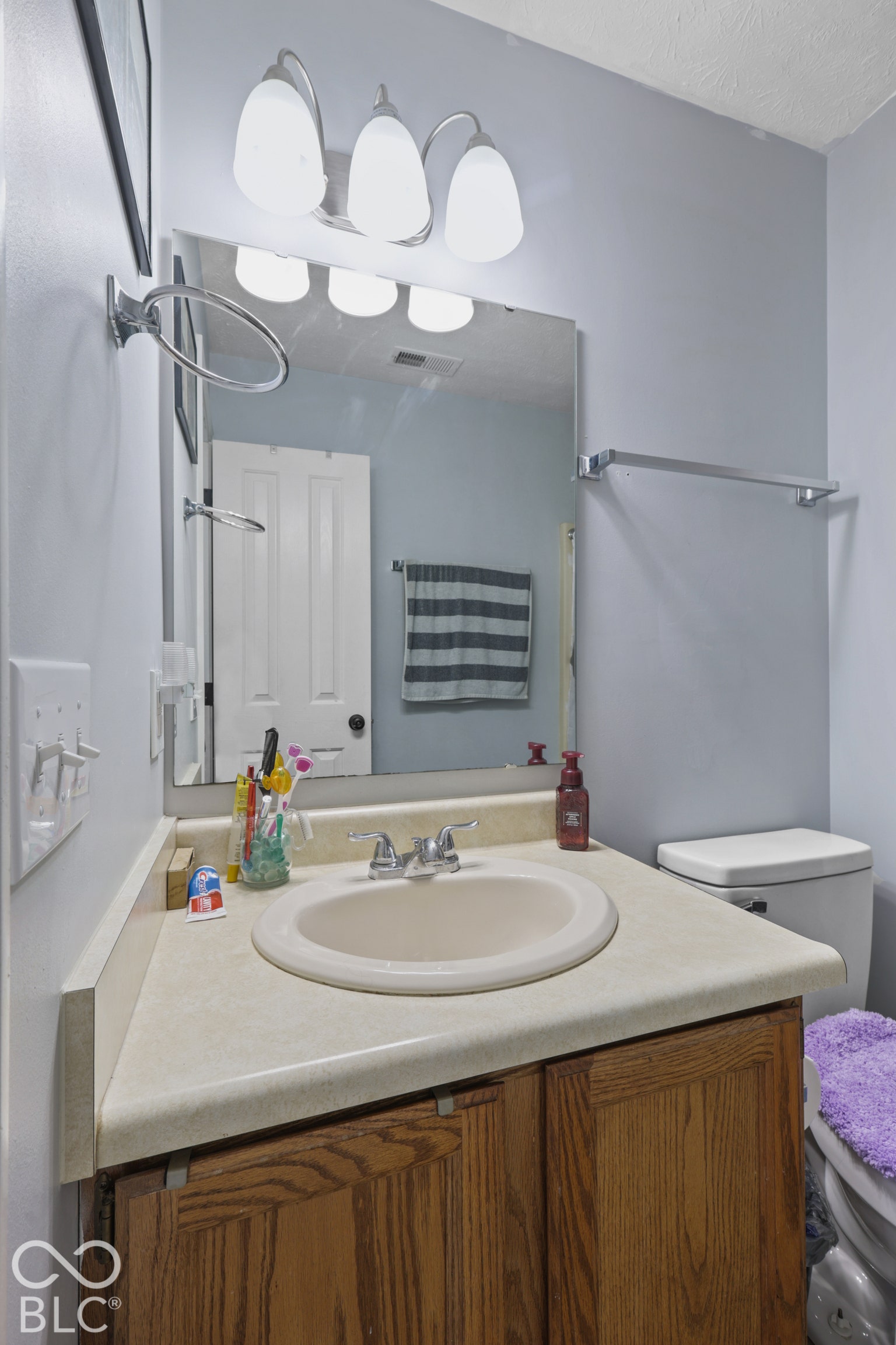 Vanity with a laminate countertop, integrated sink, and wood-finish cabinetry