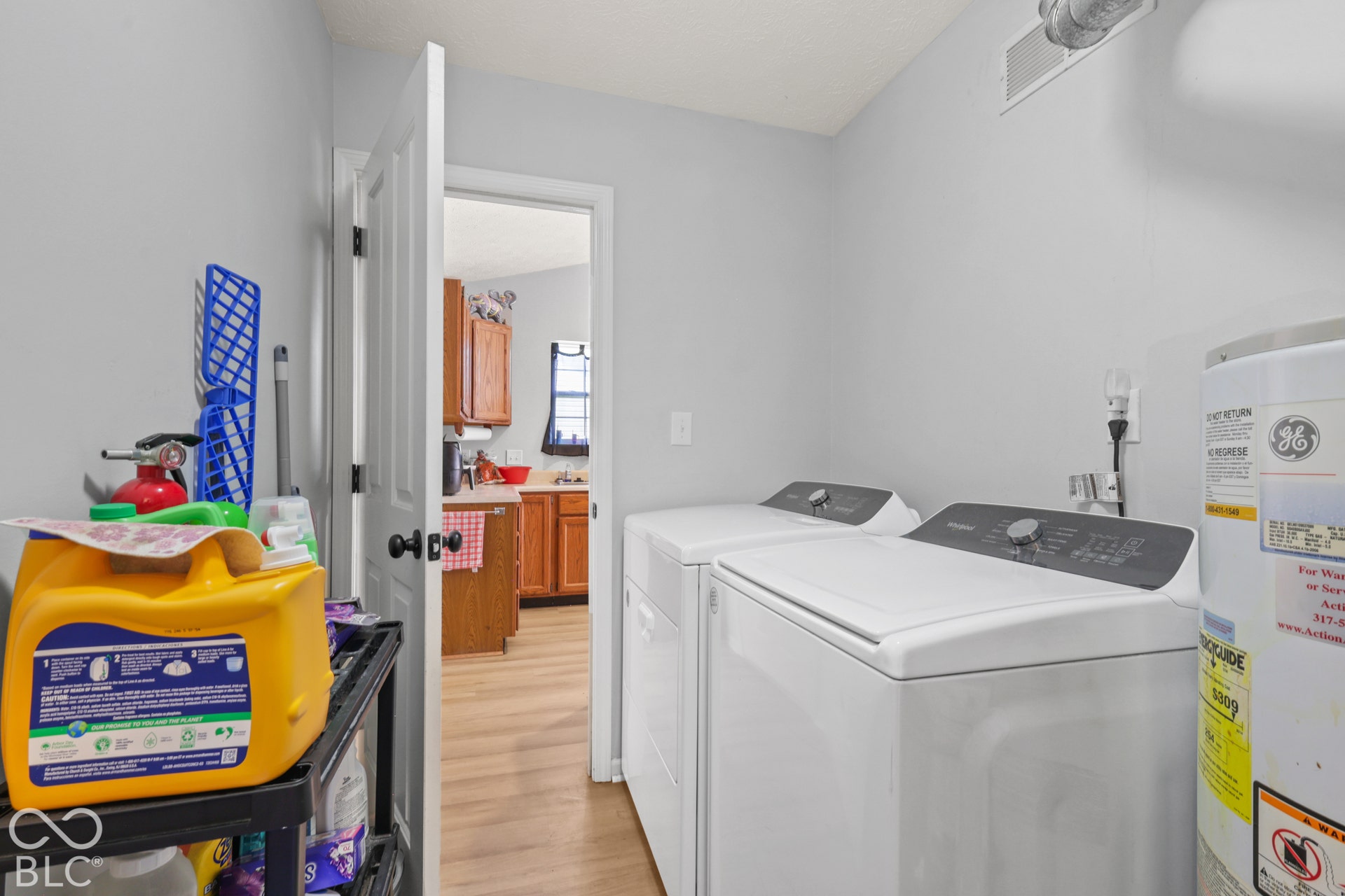 Laundry area with light gray walls, built-in water heater, and wood-finish flooring
