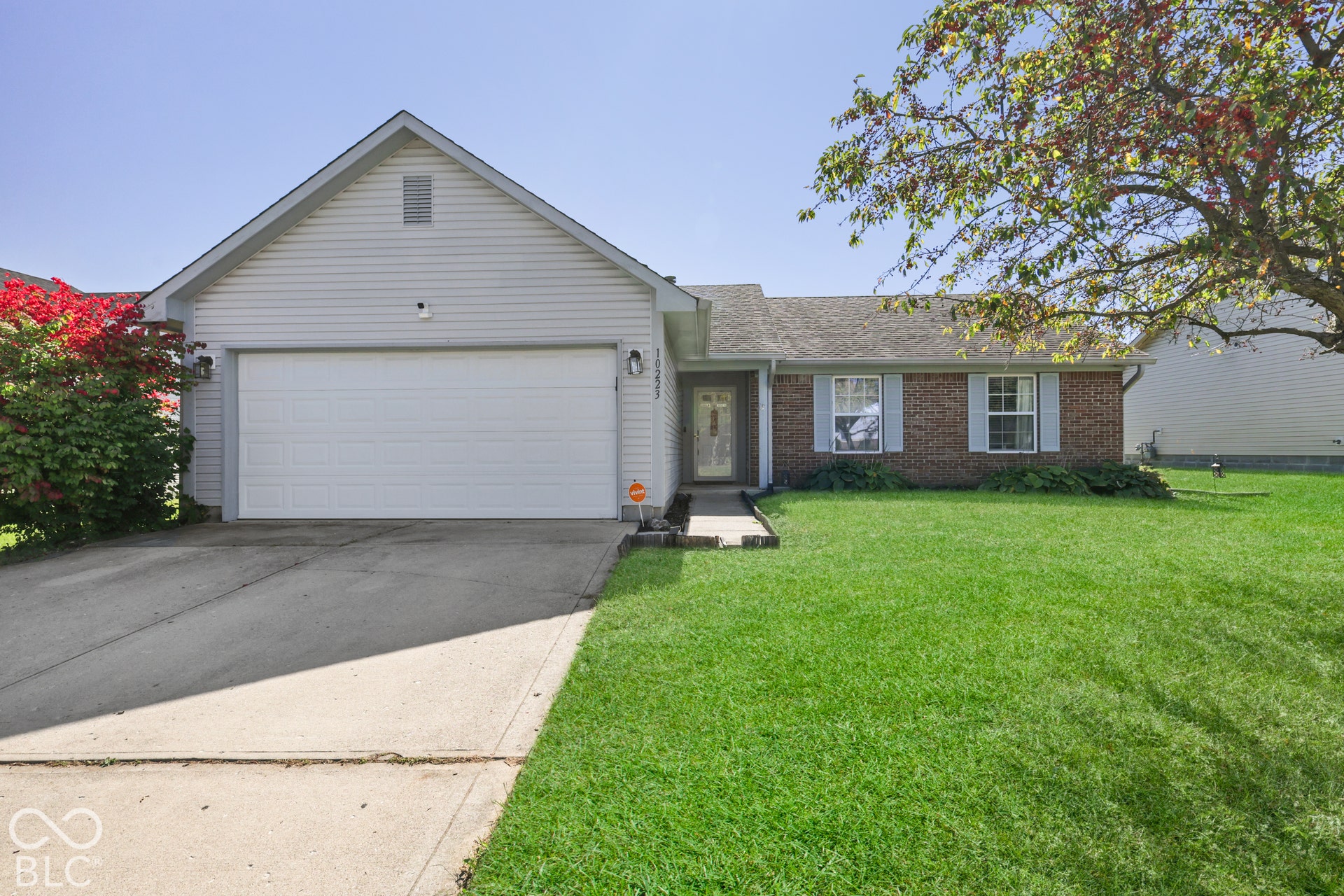 Brick and siding exterior with a gabled roofline, attached garage, and a concrete driveway