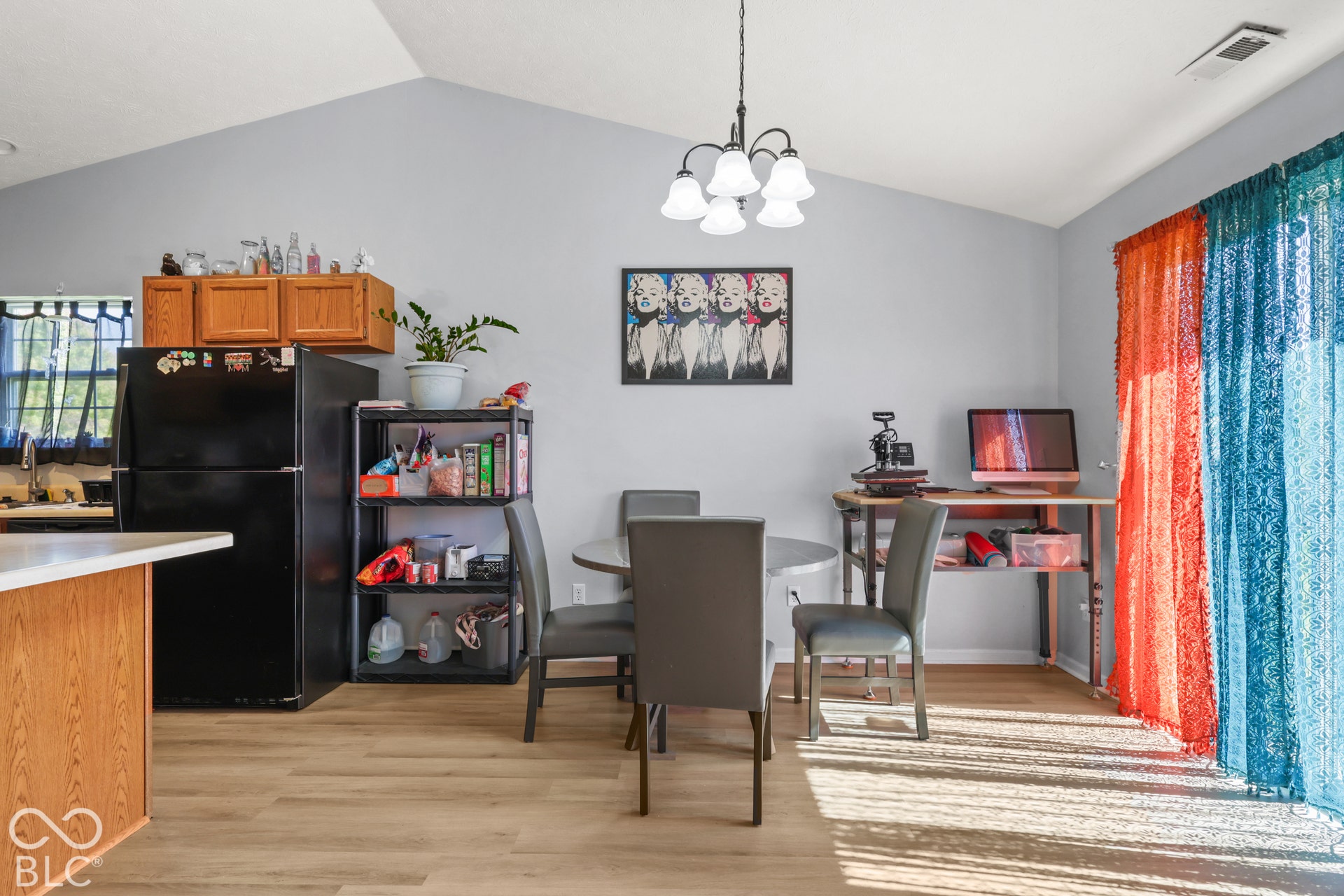 Vaulted ceiling, wood-finish flooring, wood cabinetry, built-in breakfast bar, and a contemporary chandelier