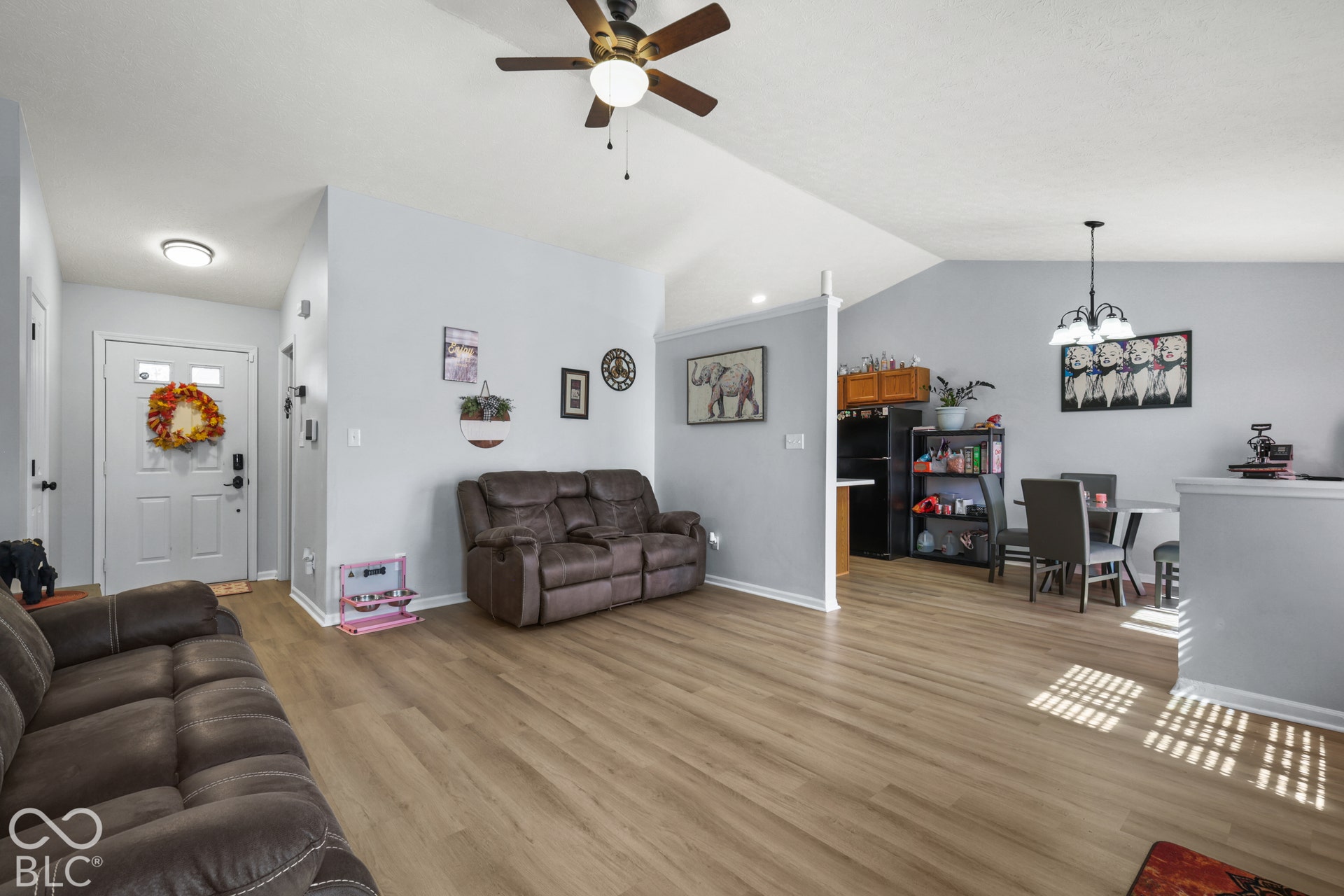Wood-finish flooring throughout, vaulted ceilings, and a ceiling fan with integrated lighting