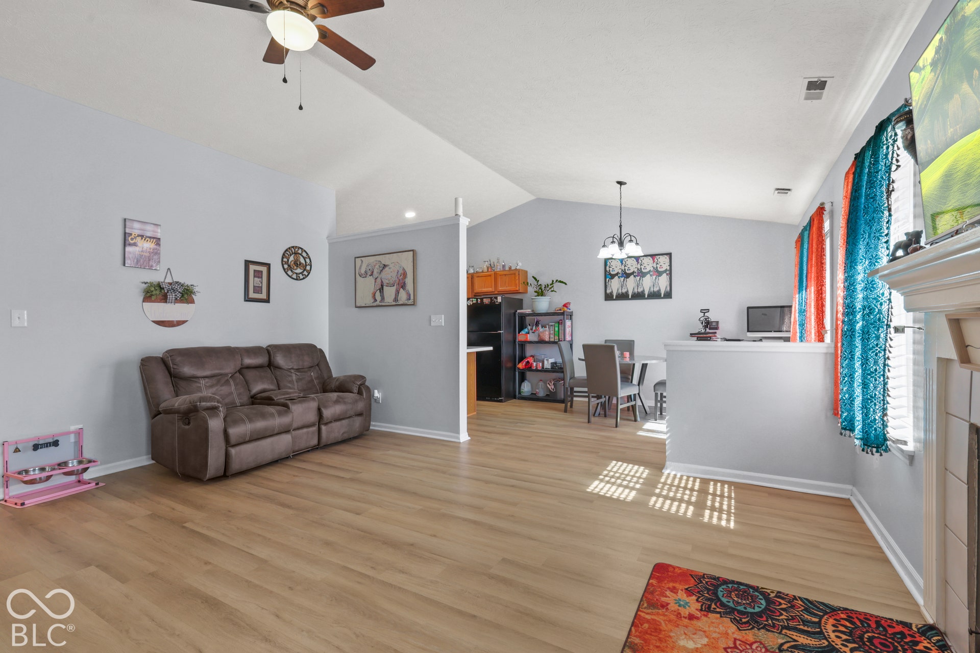 Vaulted ceilings with a ceiling fan, wood-finish flooring, and a decorative fireplace