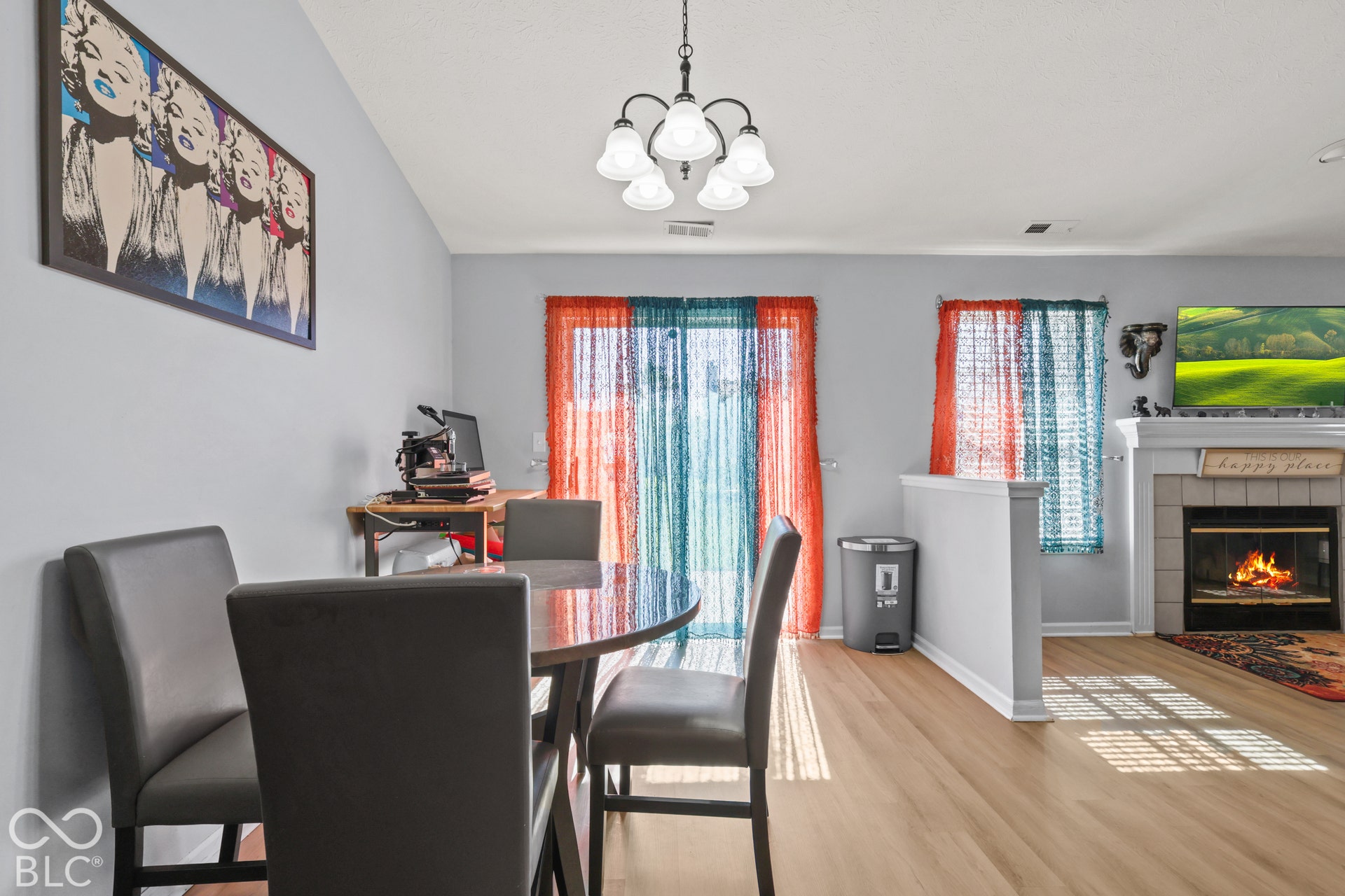 Open-concept room featuring wood-finish flooring, a fireplace with a tile surround and mantel, and an attached chandelier
