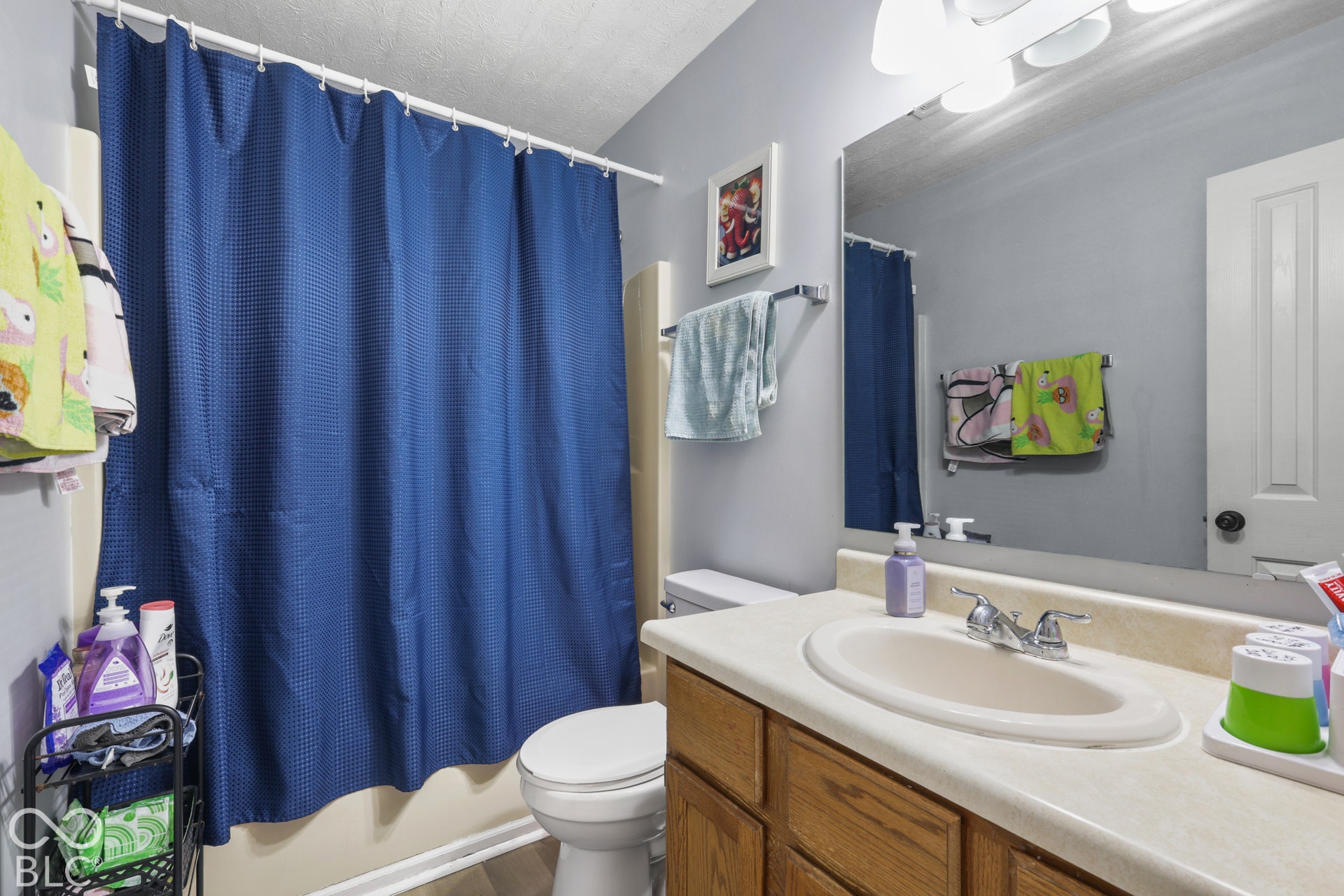Single vanity with an integrated sink and chrome faucet, wood-finish cabinetry, and a full-width wall mirror