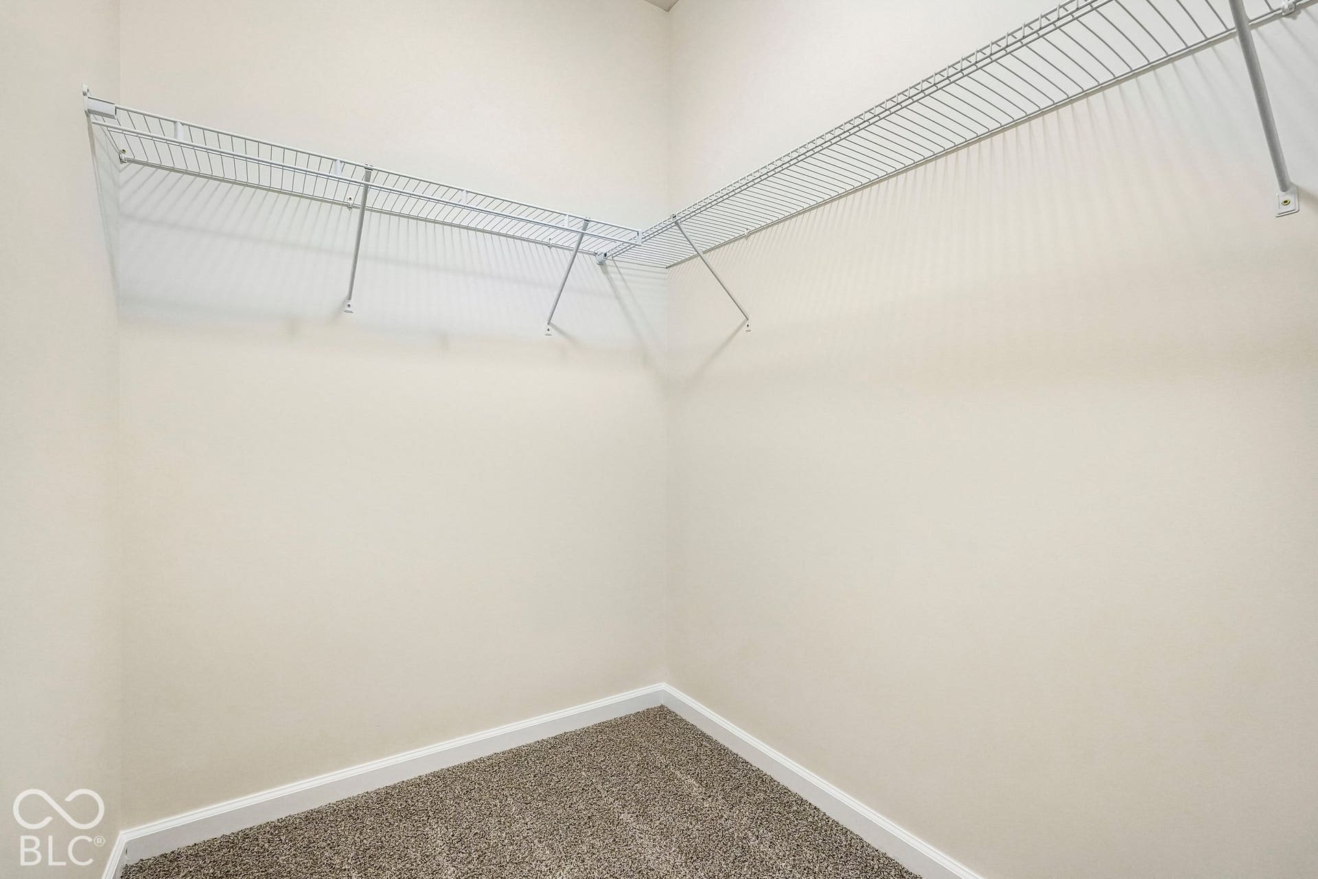 Off primary bedroom. Neutral wall paint, wire shelving, white trim, and carpeting