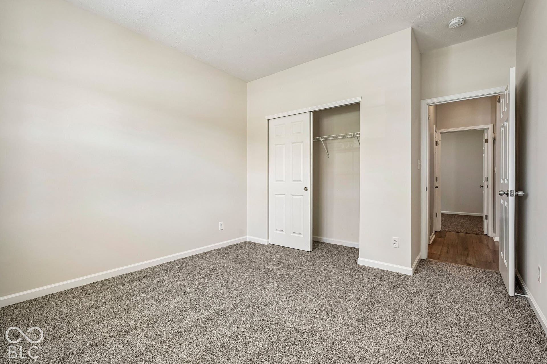 Neutral-toned walls, gray carpeting, white bi-fold closet doors, and white trim