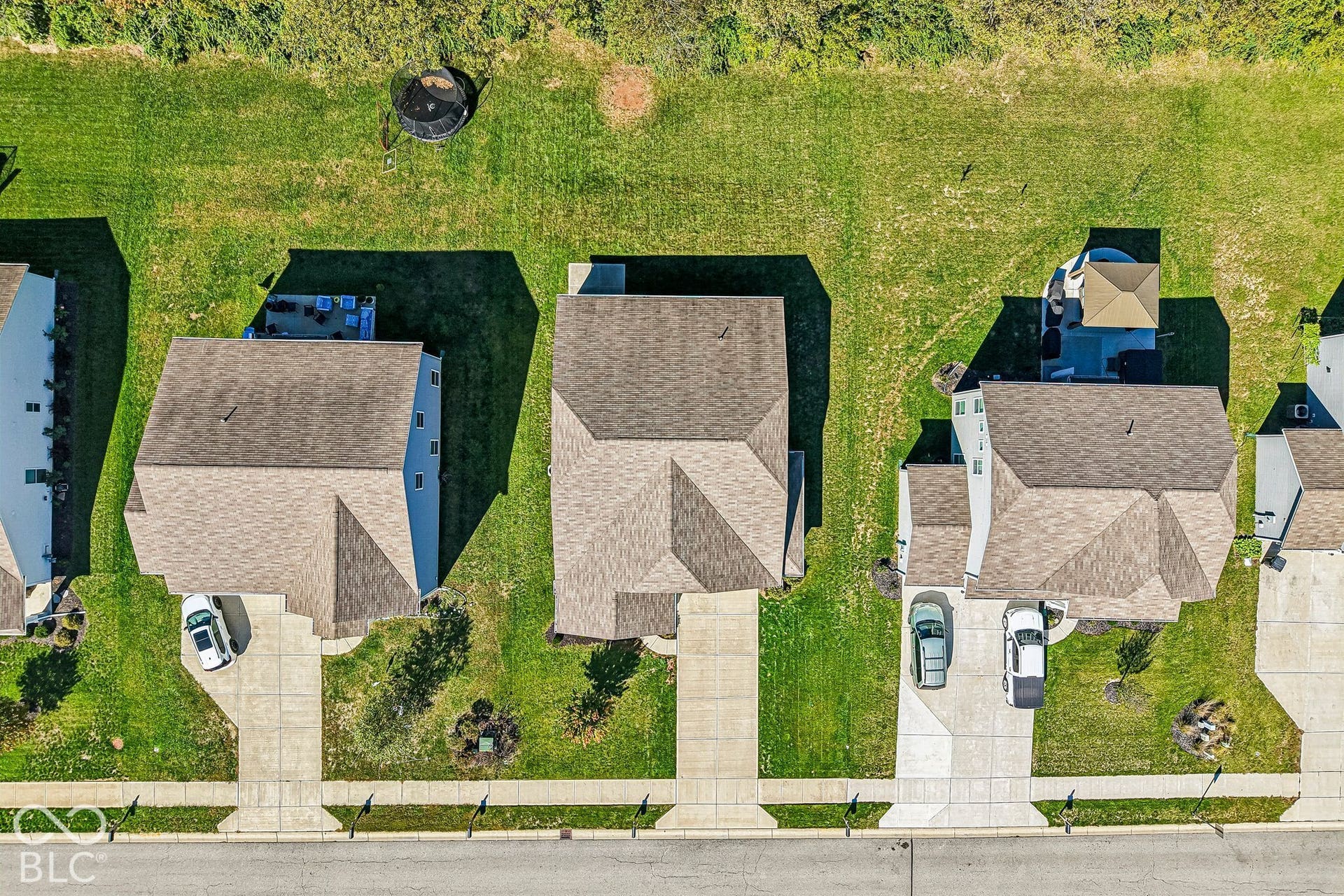 Expansive concrete driveway, attached two-car garage, and a large backyard with a paved patio