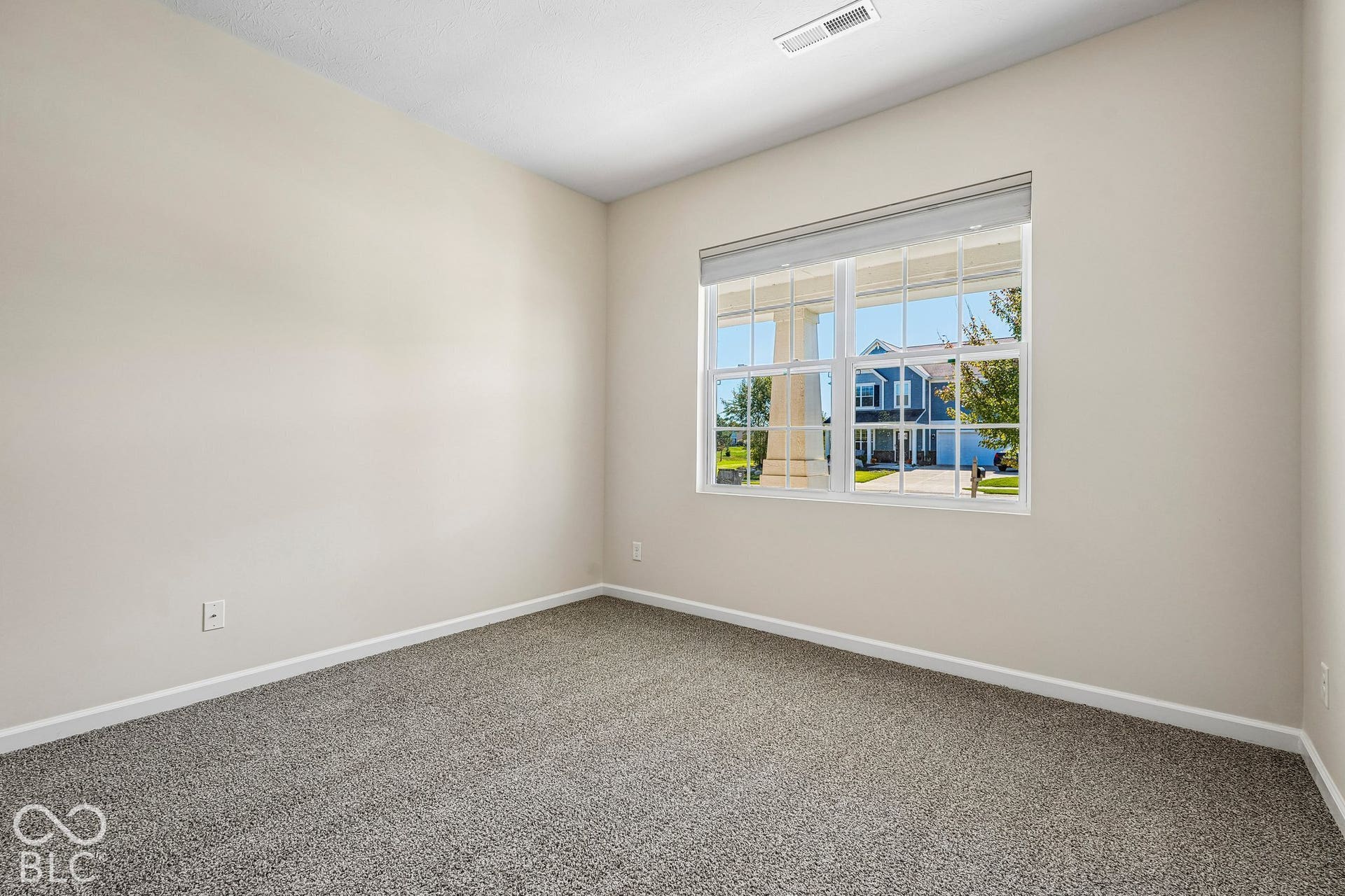 Light-toned wall paint with a textured ceiling, a double-hung window, and gray carpeting