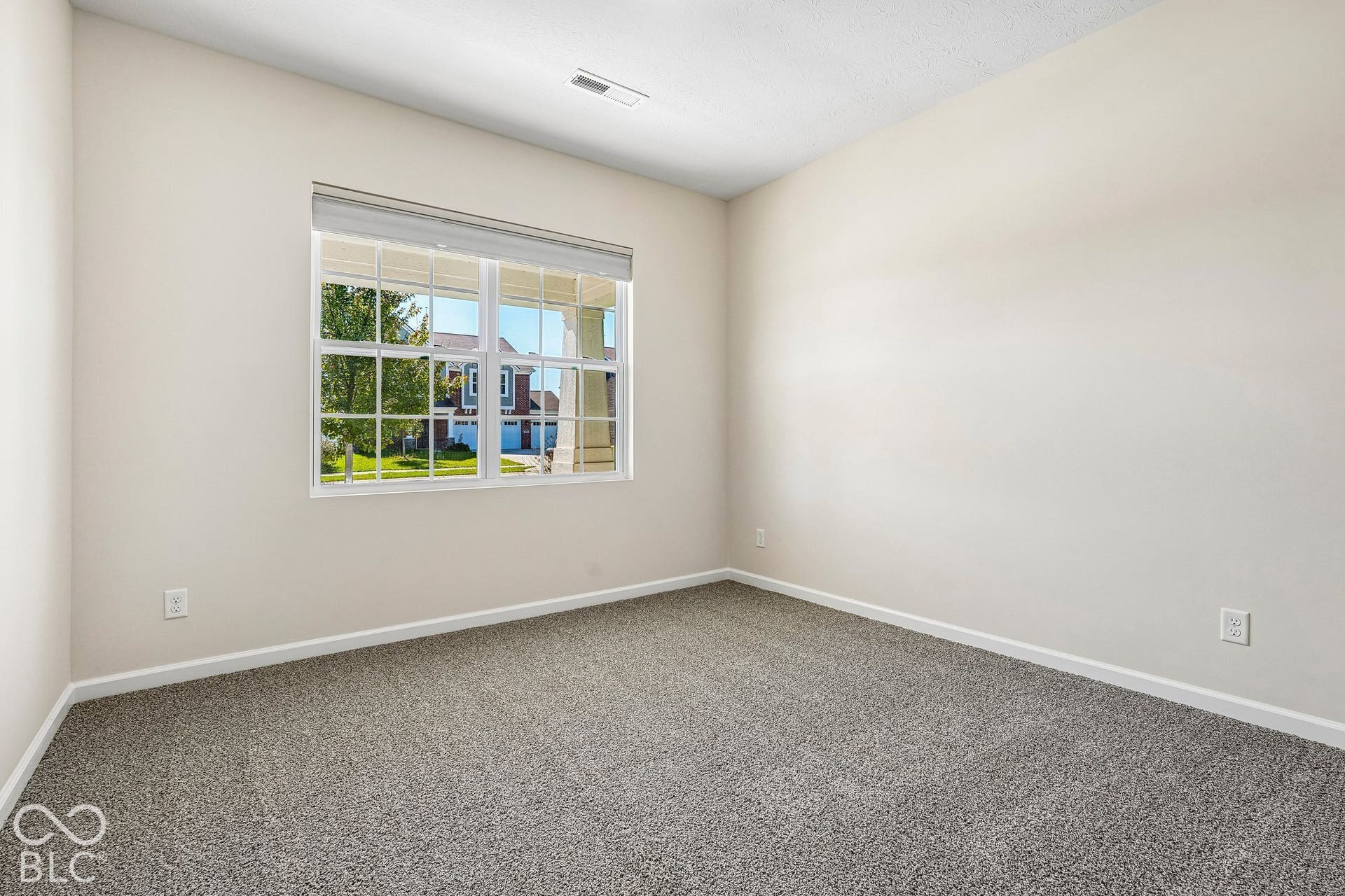 Neutral wall paint, window with white trim, and gray carpet flooring