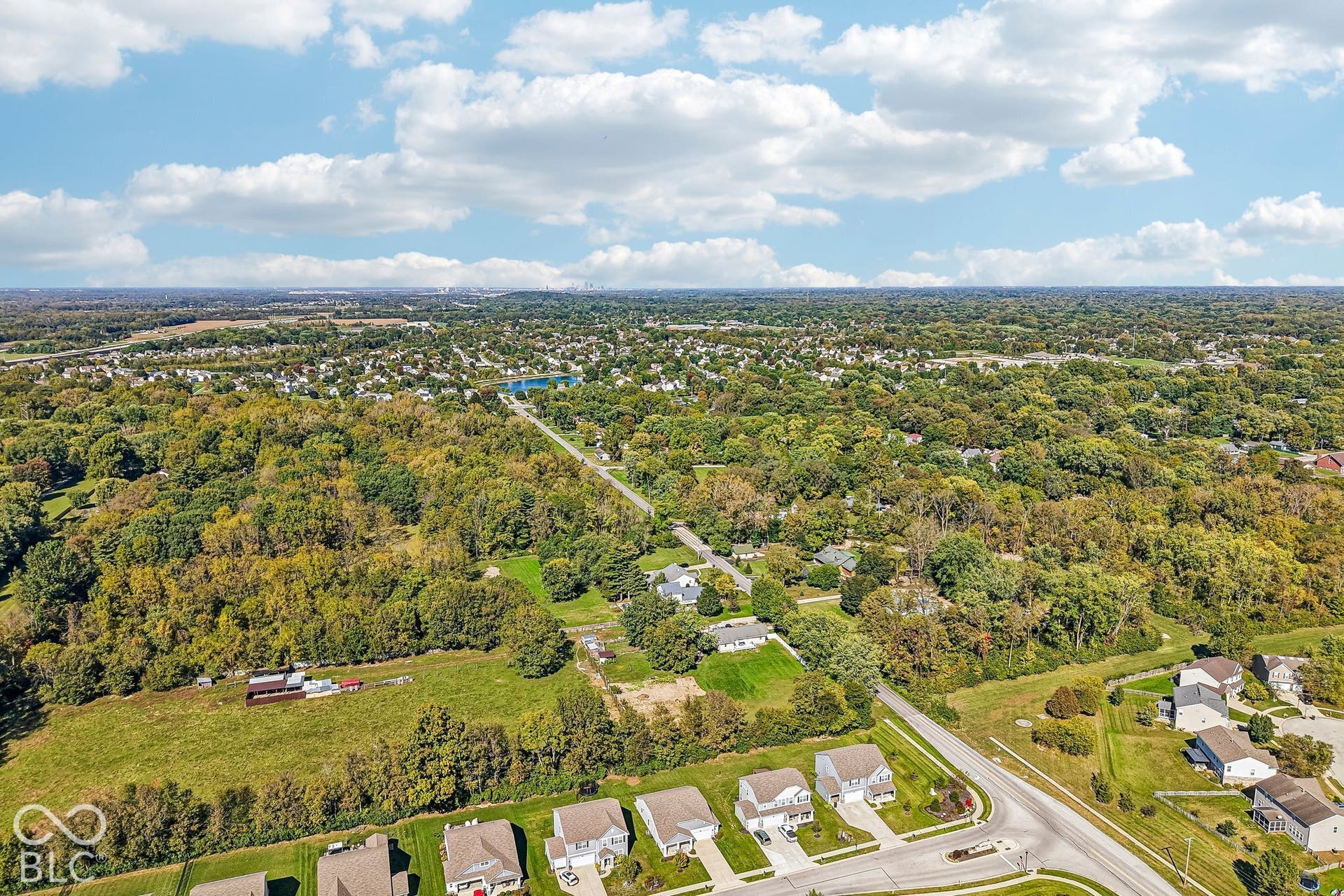 Expansive wooded terrain with a natural water feature and surrounding residential development