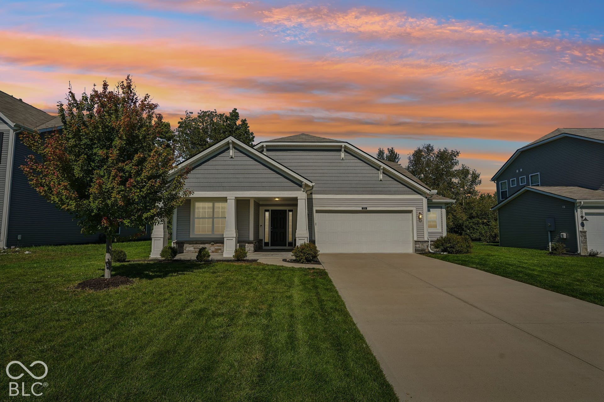 Virtually Altered - Siding exterior with stone accents, covered entry, attached garage, concrete driveway, and established lawn with a mature tree