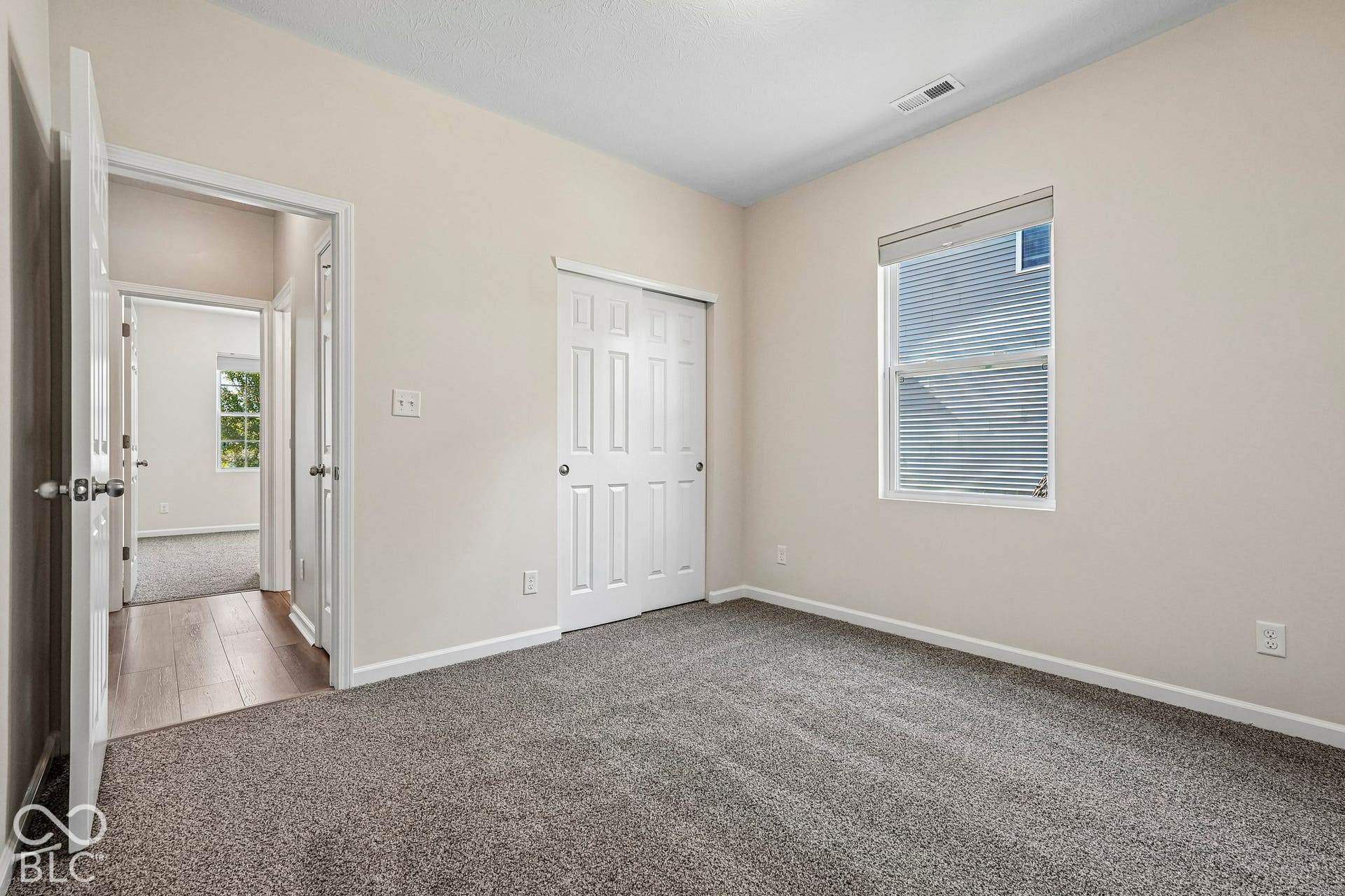 Neutral wall color, gray carpet flooring, white trim, sliding closet doors, and a window with blinds