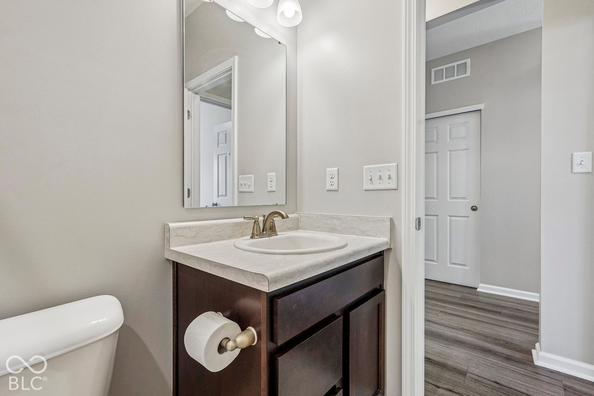 Vanity with an integrated basin, brushed nickel faucet, and a wall-mounted mirror