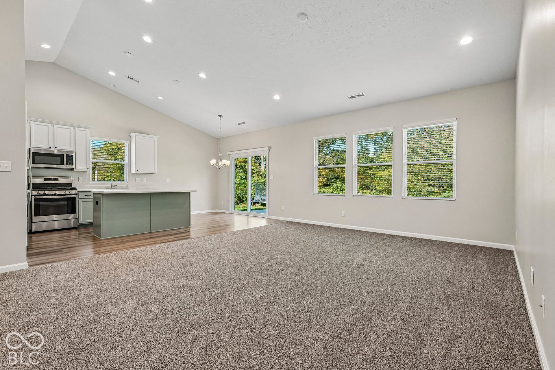 Vaulted ceiling, recessed lighting, wood-finish flooring, stainless steel appliances, and a sliding glass door