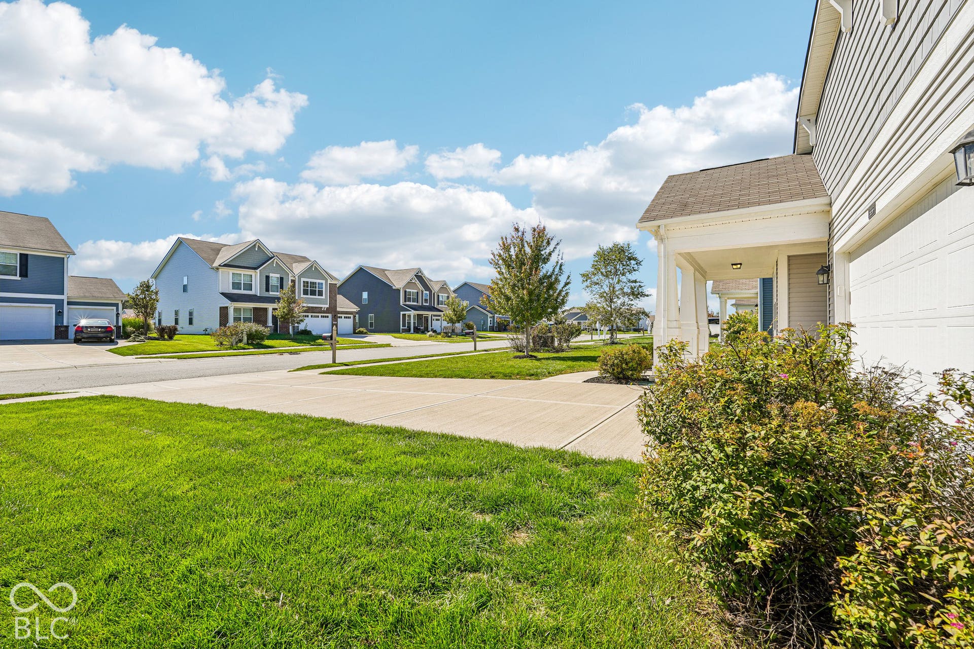 Entryway featuring a covered porch with white columns, concrete driveway, and attached two-car garage