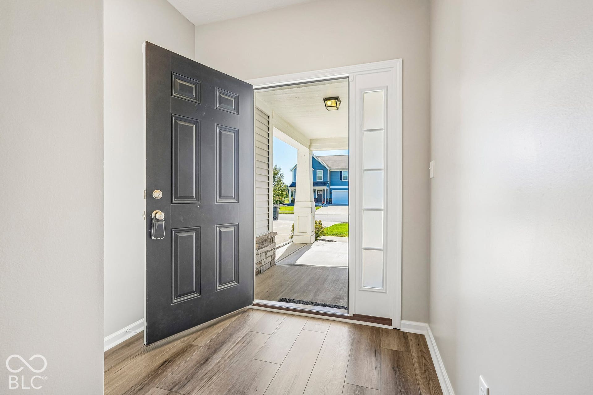 Panel door entry with decorative sidelights, wood-finish flooring, and light wall tones