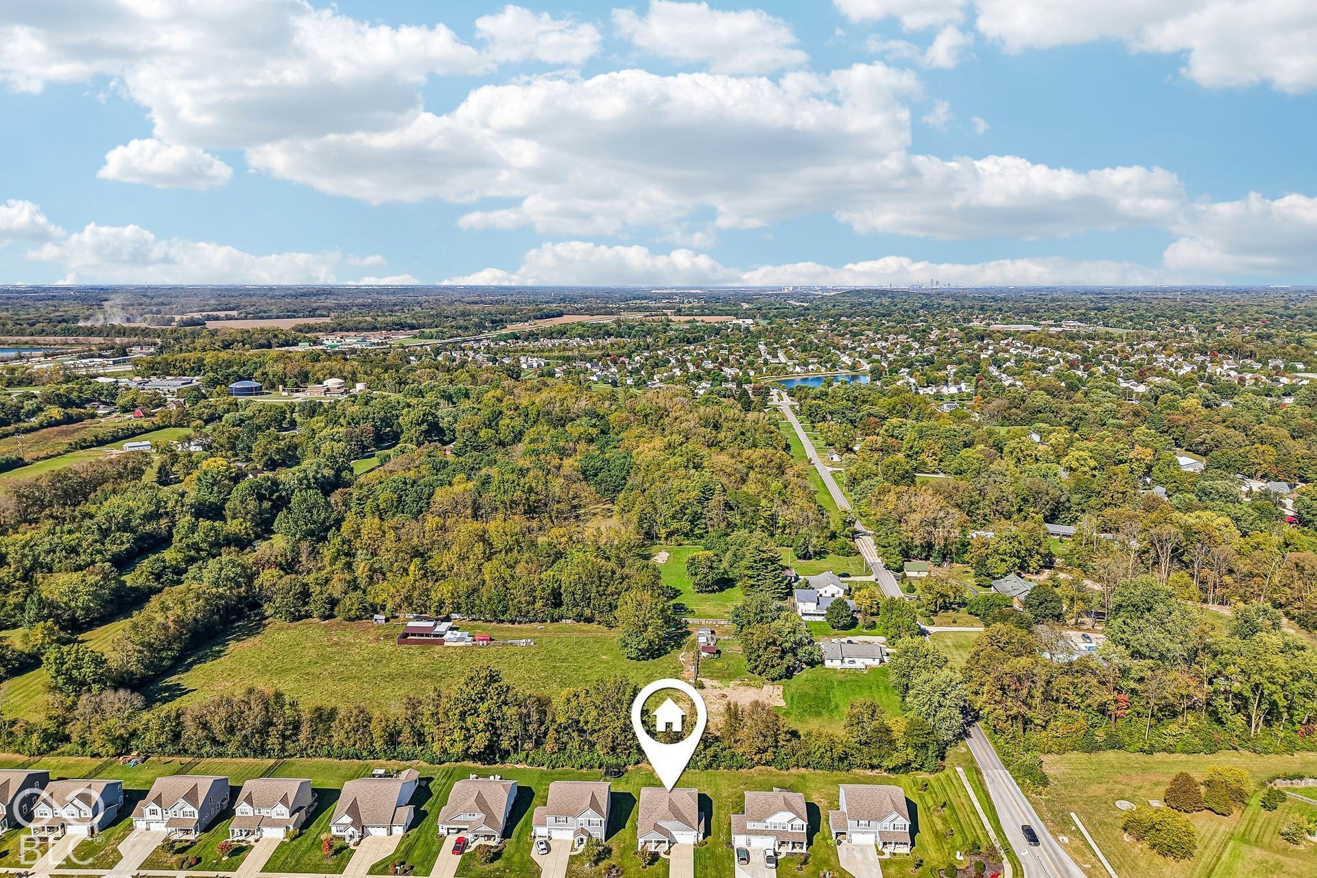 Aerial perspective showcasing the residential street, surrounded by extensive tree cover and open green spaces