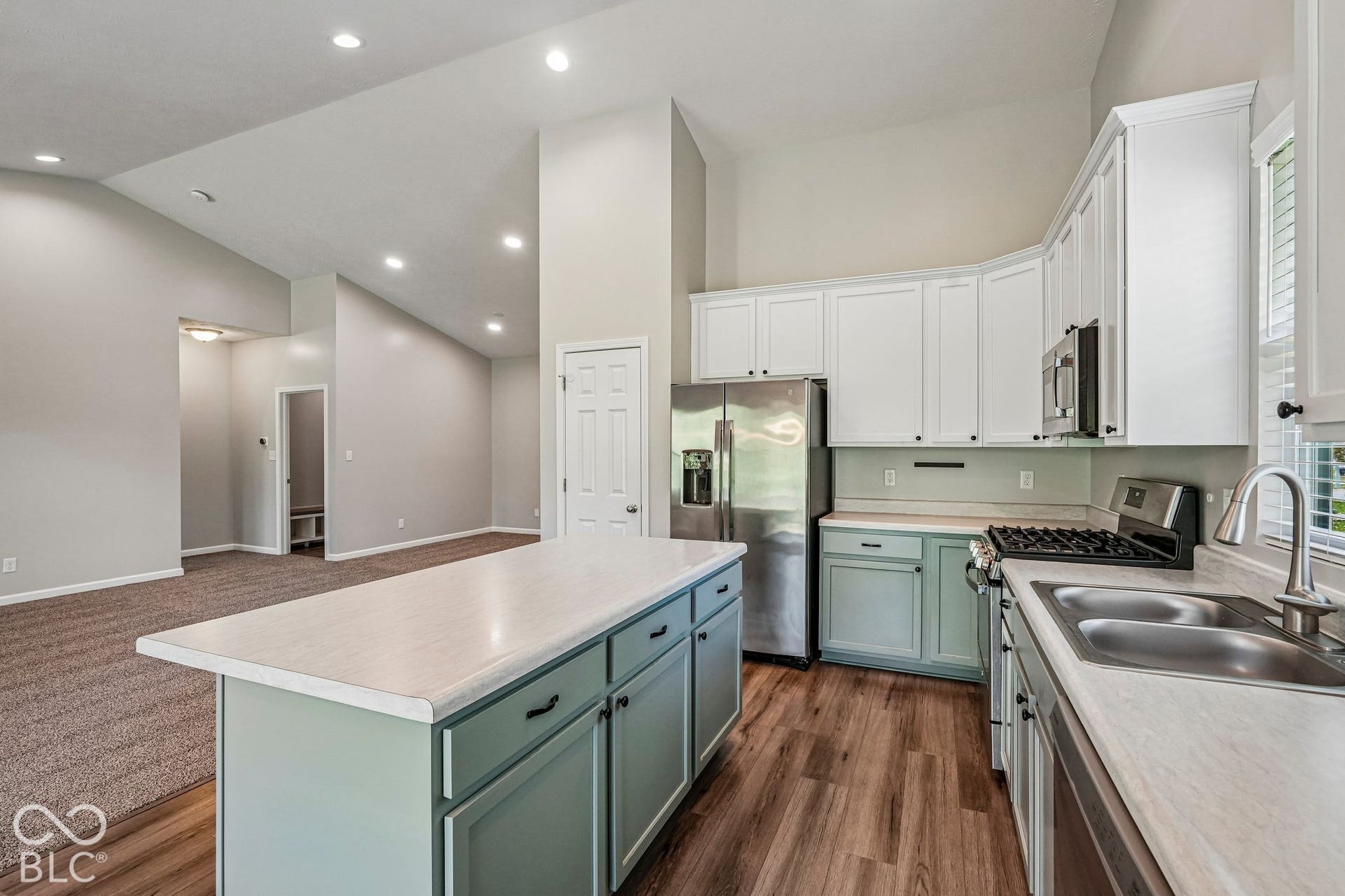 Kitchen featuring a center island, stainless steel appliances, dual-basin sink, and ample white cabinetry