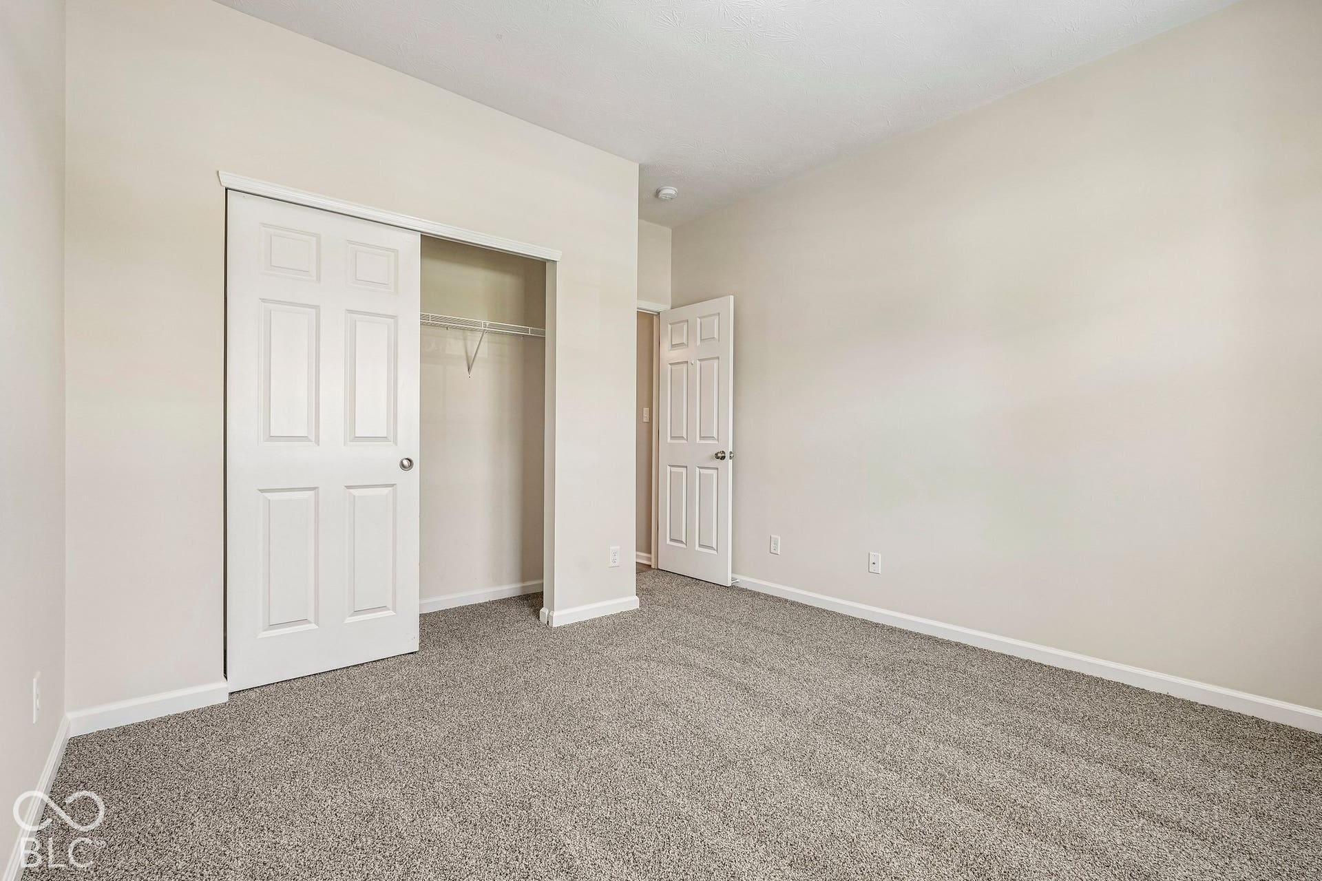 Plush carpeting, light neutral wall paint, and a built-in closet with sliding panel doors