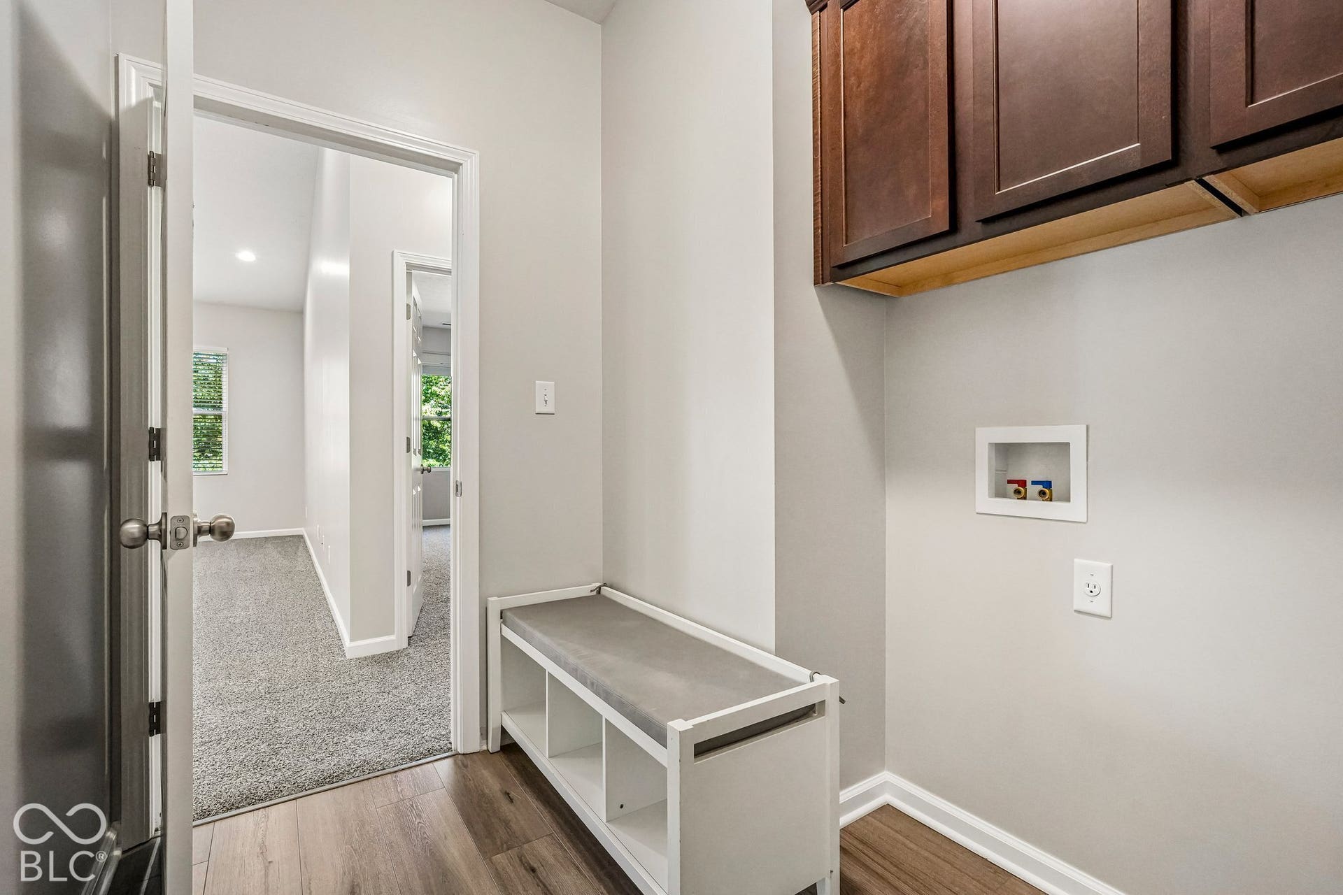 Wood-finish flooring, built-in cabinetry, modern door hardware, and light neutral wall colors