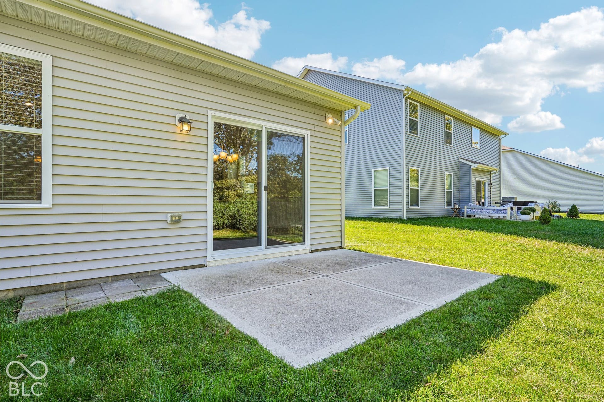 Exterior featuring horizontal siding, a sliding glass door, an outdoor wall light, and a concrete patio