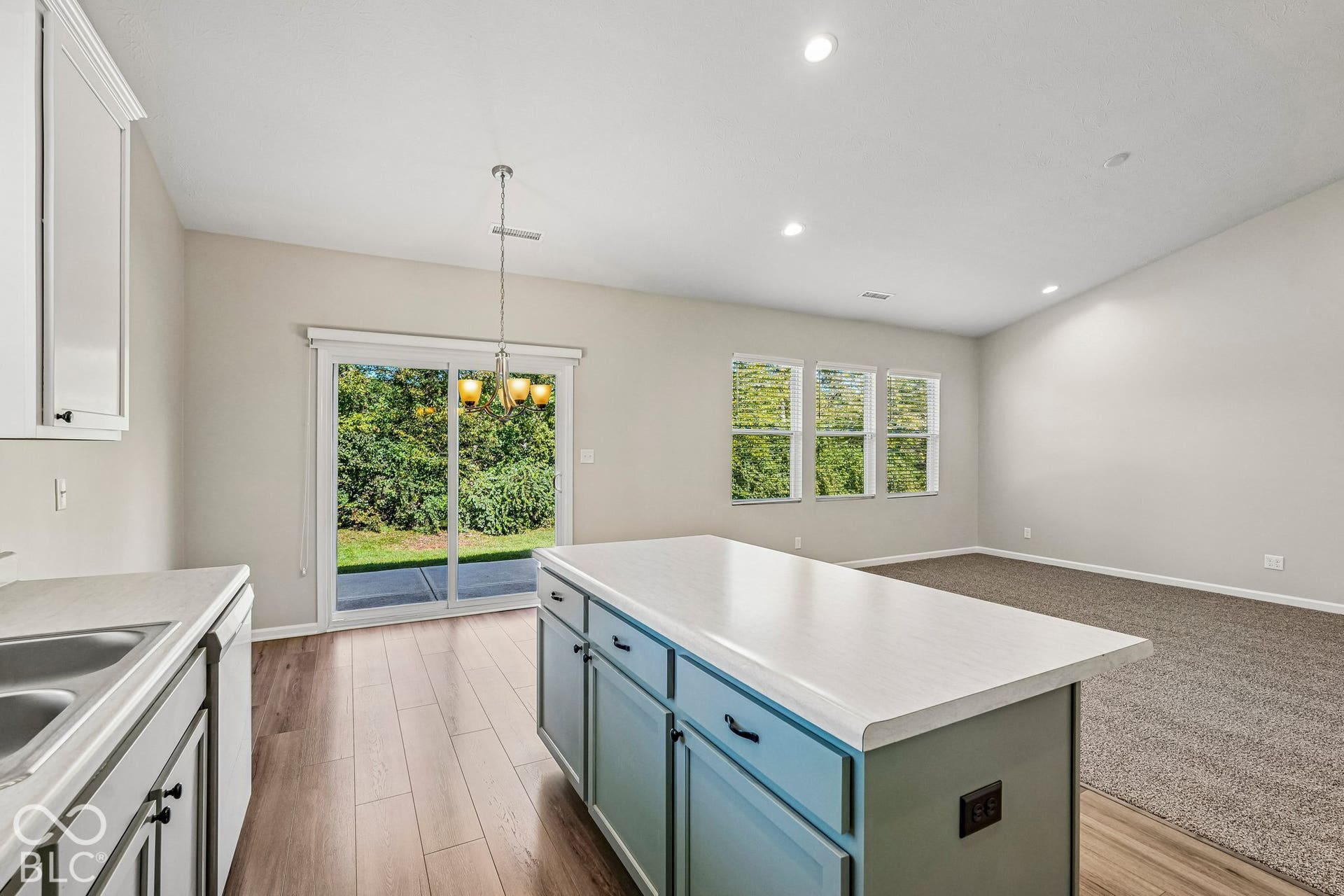 Kitchen island with a light-toned countertop, wood-finish flooring, recessed lighting, and sliding glass door